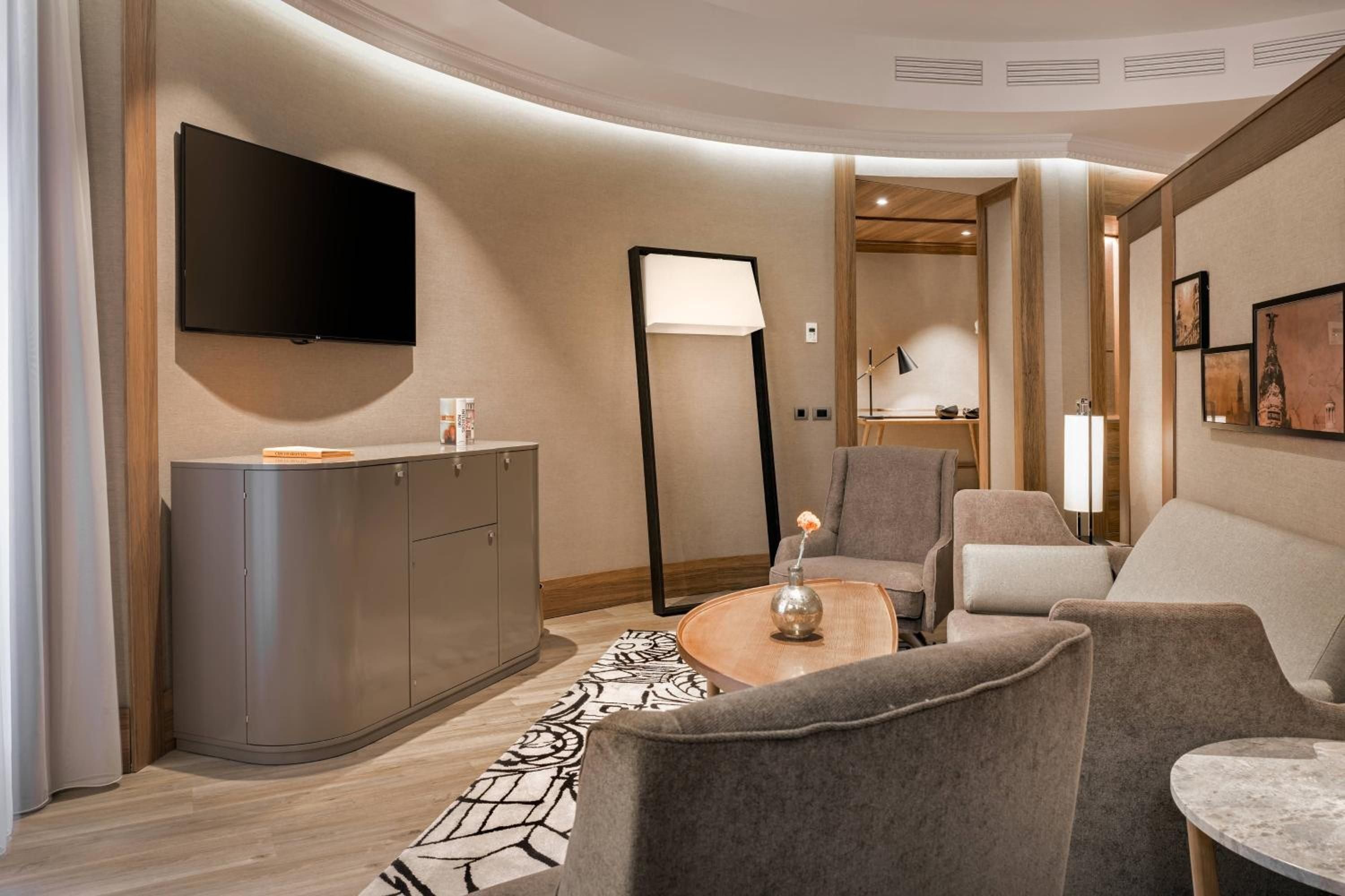 Curved walls and warm wood accents create an intimate sanctuary where contemporary design meets cozy comfort in this thoughtfully appointed suite's living area.