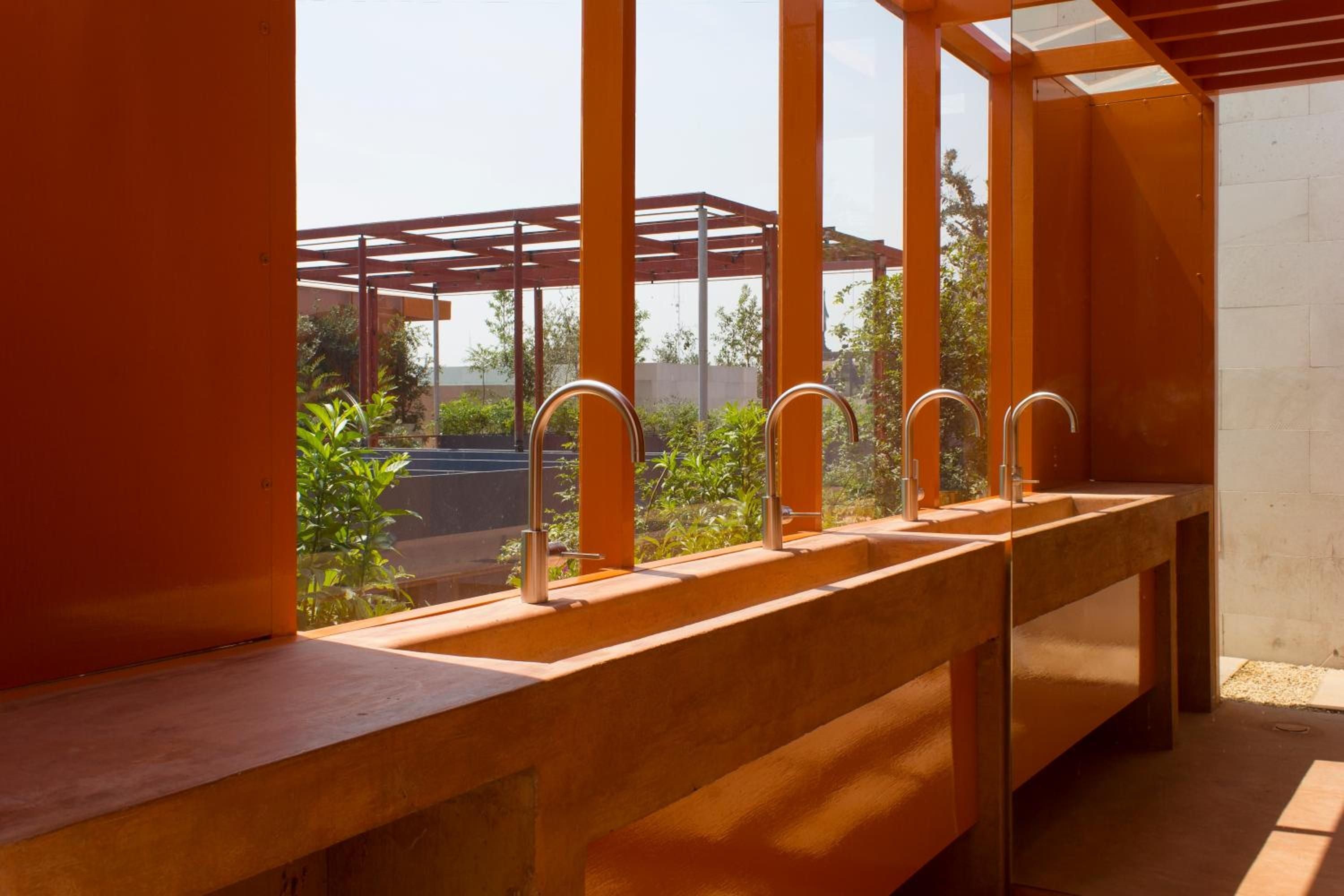 Warm terracotta surfaces and sleek copper faucets create a striking wash station where desert modernism meets tactile luxury in this open-air spa pavilion.