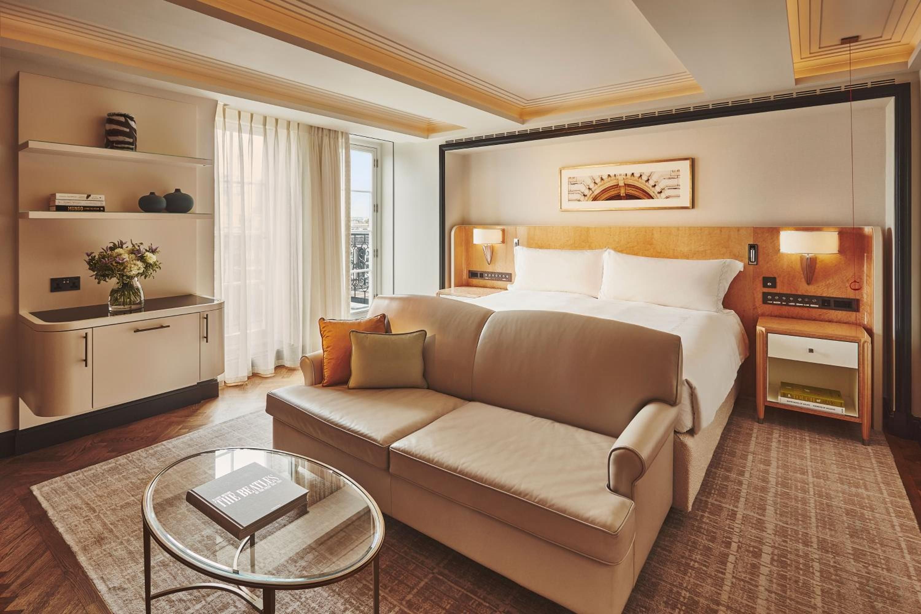 Warm wood tones and sumptuous taupe furnishings create an intimate sanctuary where Art Deco elegance meets contemporary comfort in this beautifully appointed suite.