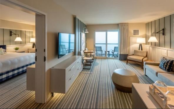 Ocean breezes drift through this sophisticated suite where striped carpeting leads to panoramic water views, while warm wood paneling creates an intimate coastal retreat.