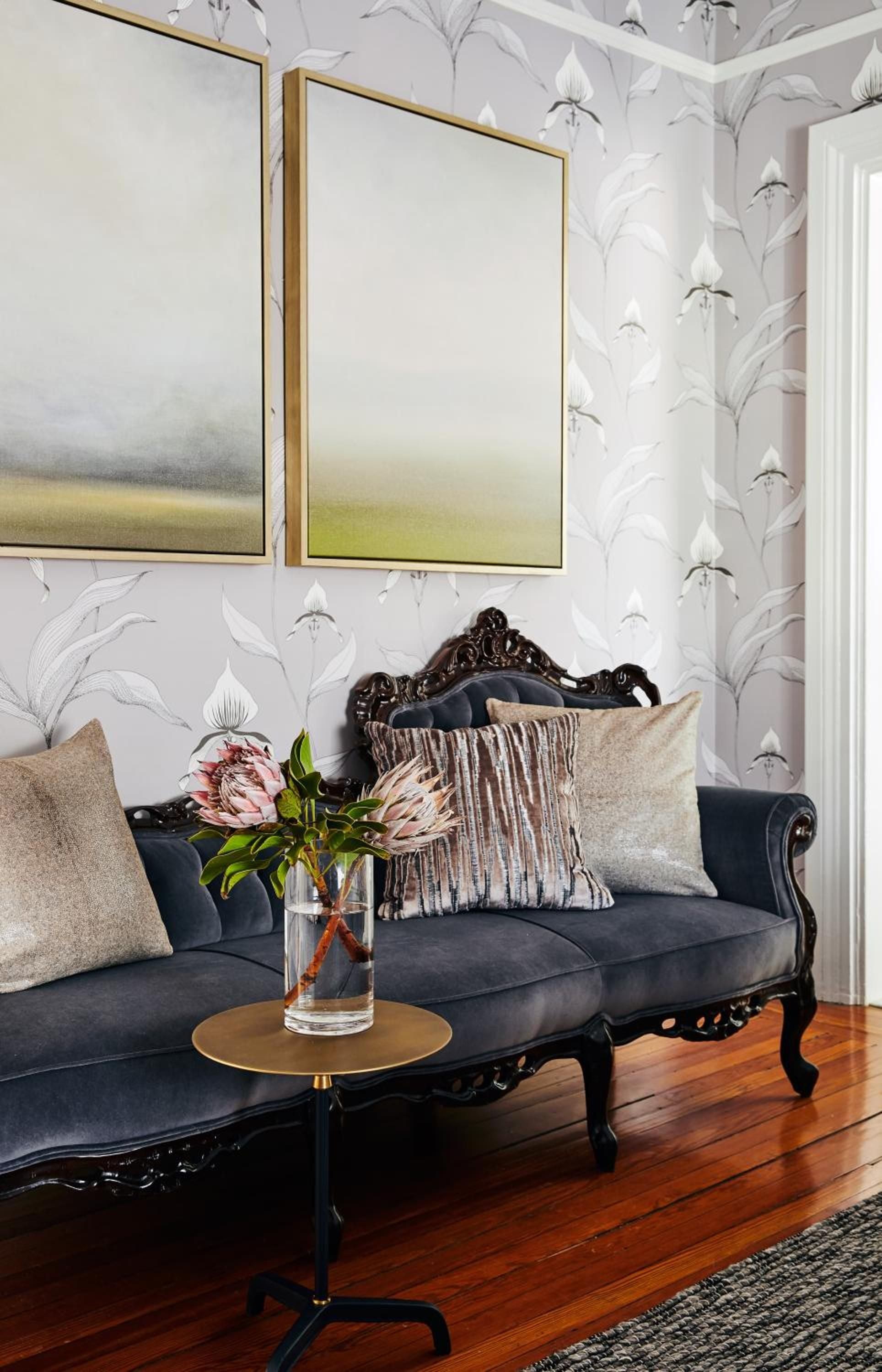 Ornate Victorian furniture meets botanical wallpaper in this intimate corner, where abstract art and fringed pillows create an unexpectedly modern conversation.