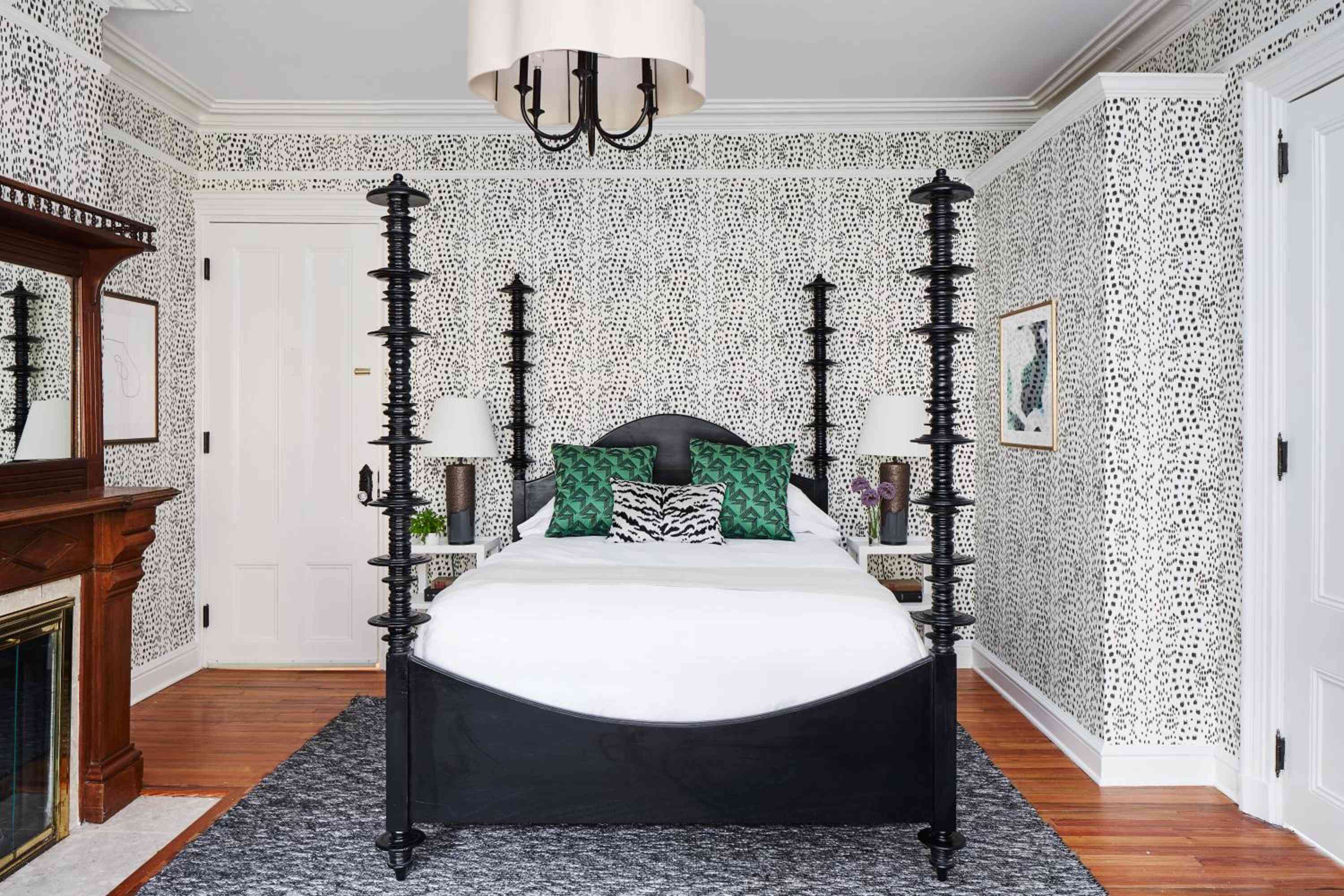 Bold leopard print wallpaper envelops this dramatic guest room, where a colonial four-poster bed anchors the space beneath an elegant drum shade chandelier.
