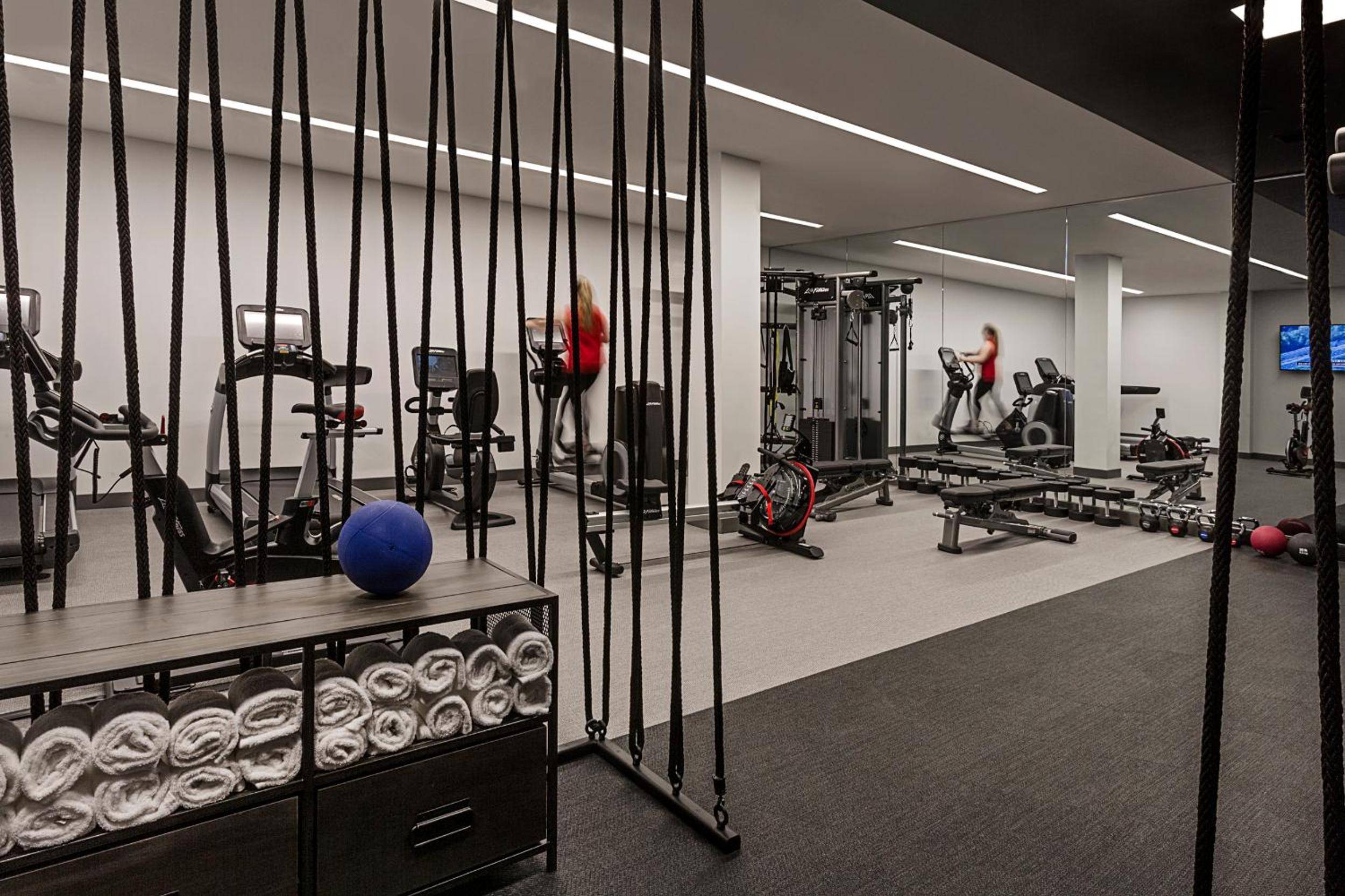 Suspended training ropes frame this sleek fitness sanctuary, where polished concrete floors and streamlined equipment create an energizing backdrop for morning workouts.
