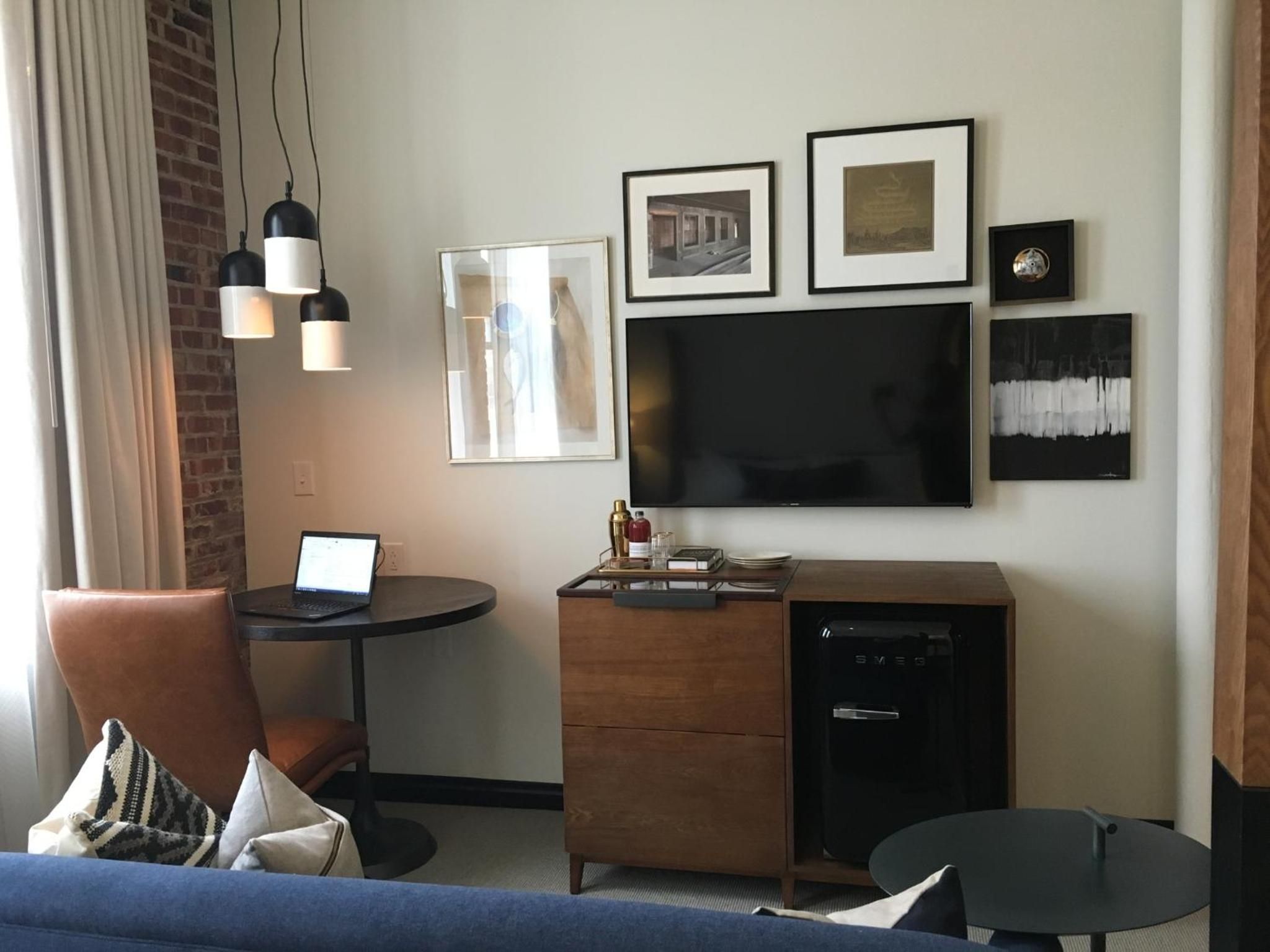 Mid-century modern furnishings and curated artwork create an intimate workspace corner, where pendant lights cast warm glows over polished surfaces and thoughtful design details.