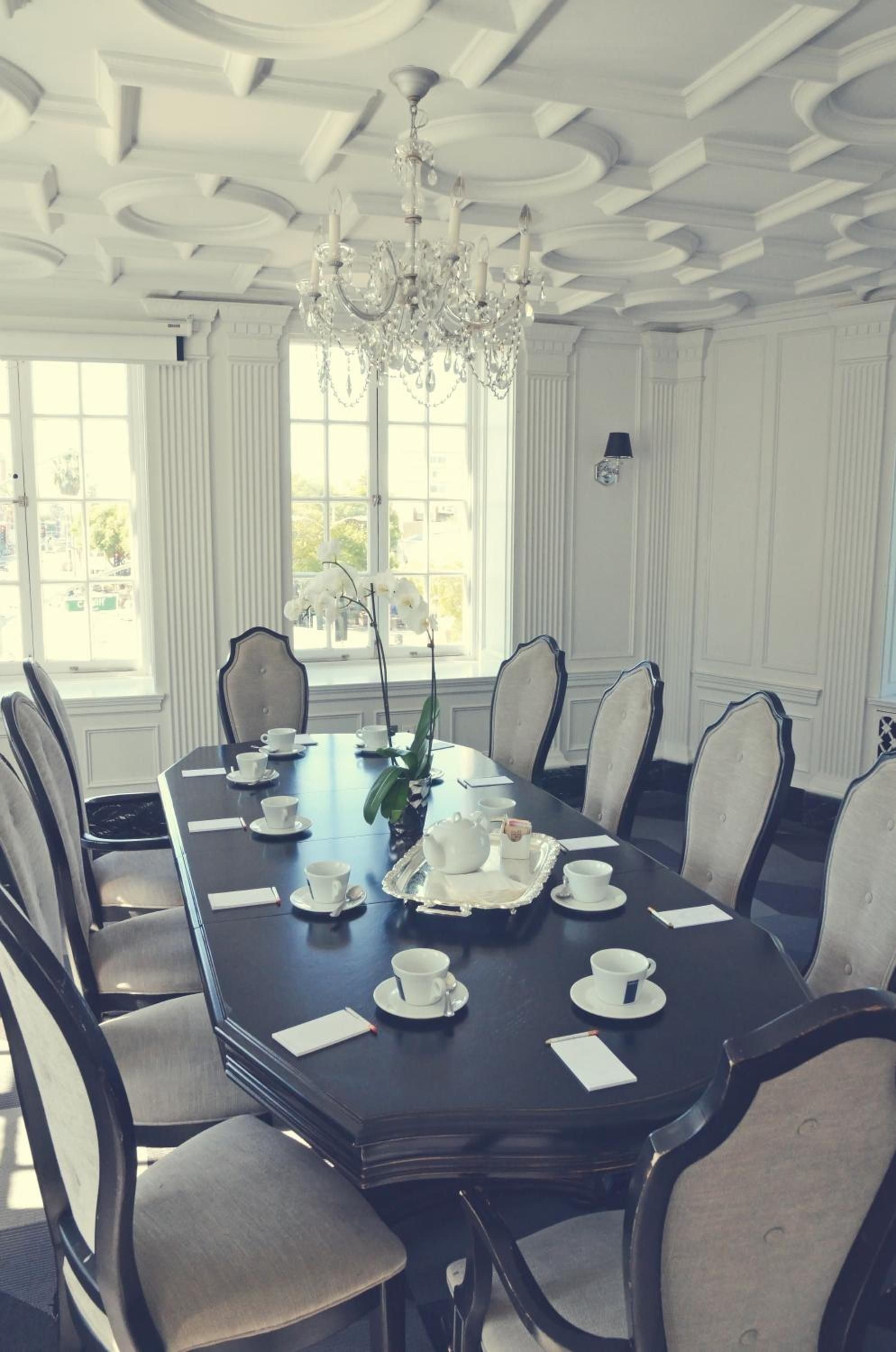 Ornate coffered ceilings and crystal chandeliers frame intimate gatherings around the polished mahogany table, where white orchids and bone china create moments of refined elegance.
