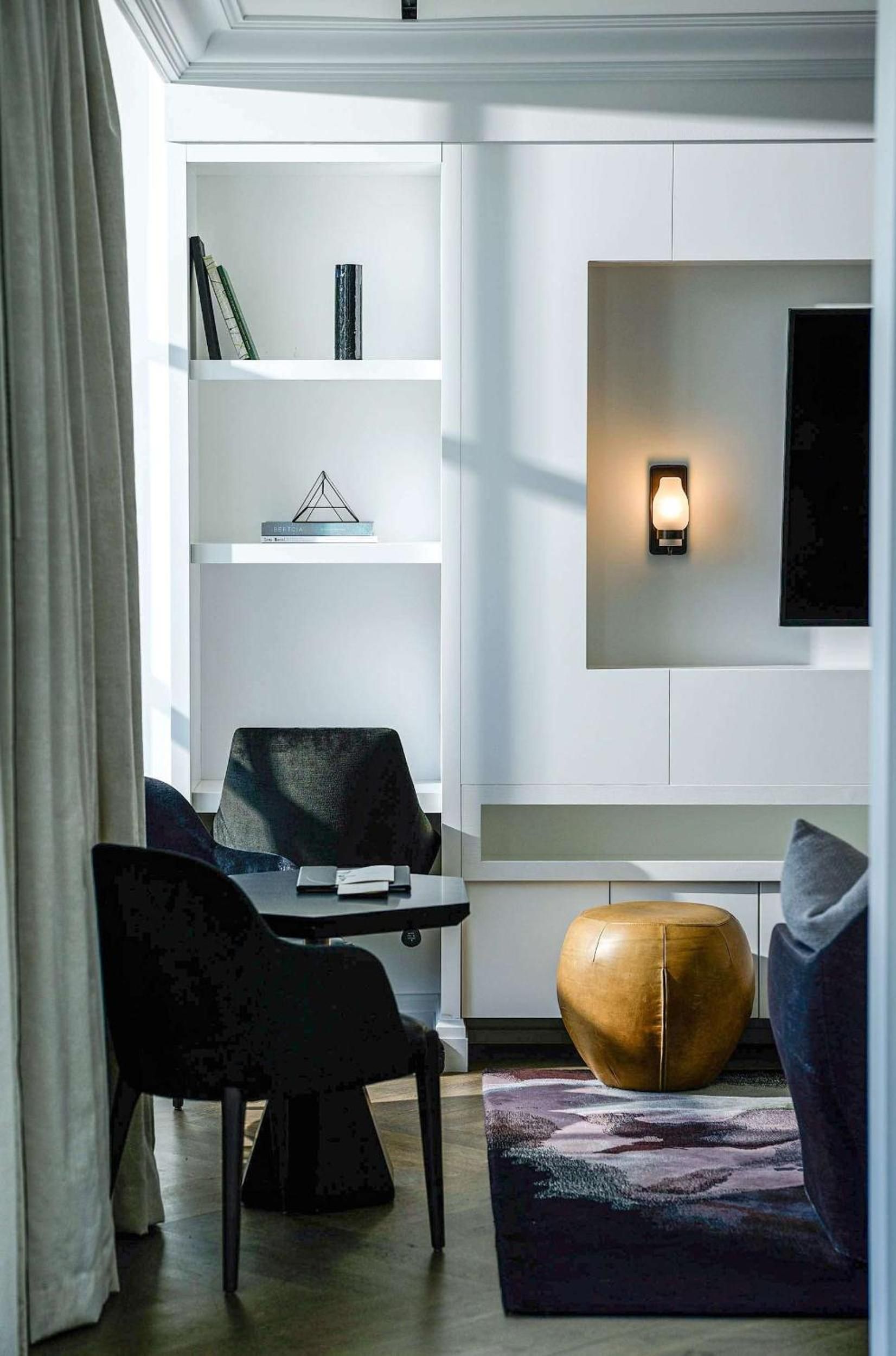 Sophisticated built-in shelving and warm sconce lighting create an intimate reading nook, while rich leather and geometric textures add layers of contemporary comfort.