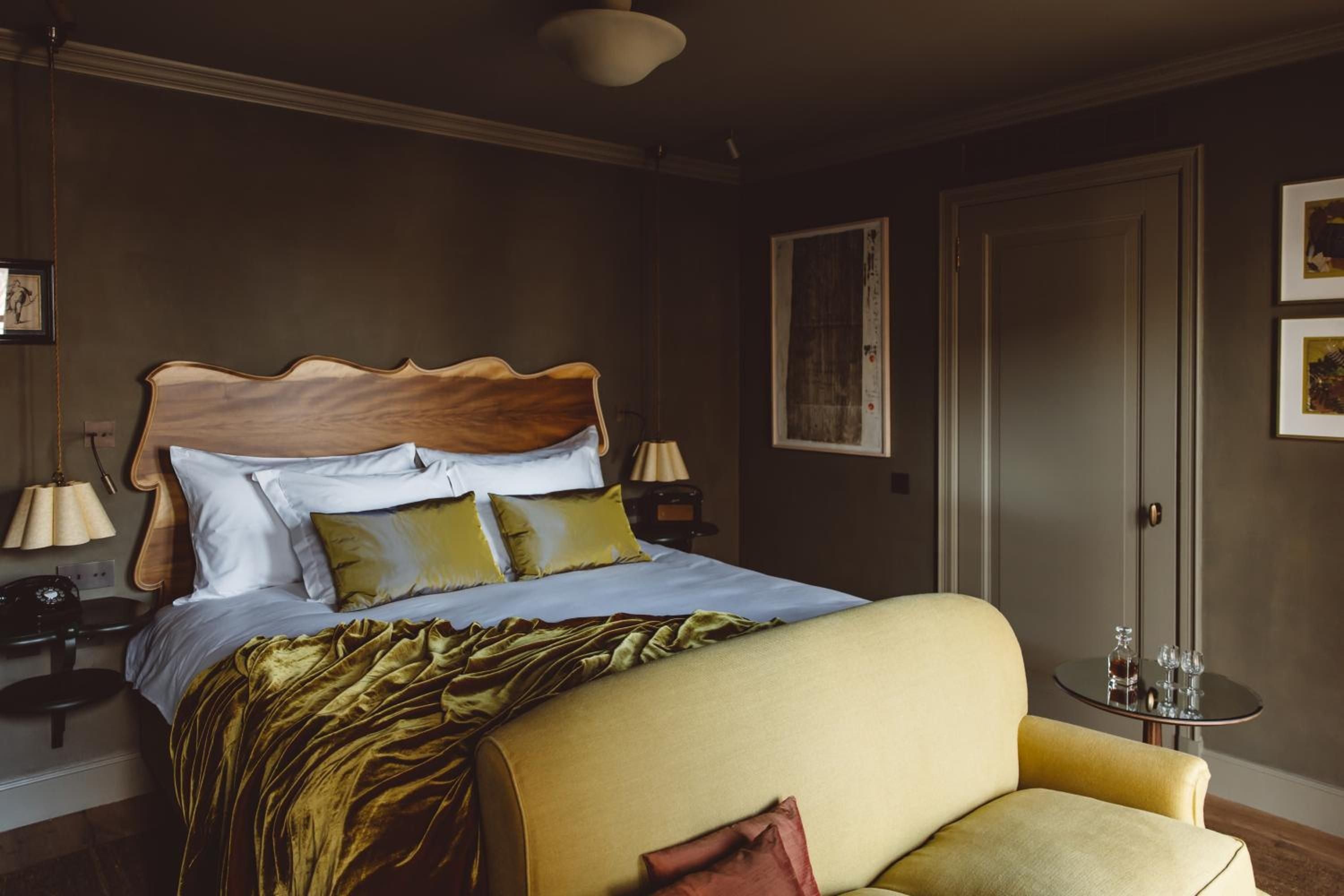 Warm amber light pools across velvet textures and rich wood grains, where golden throw pillows complement the moody sophistication of this intimate retreat.
