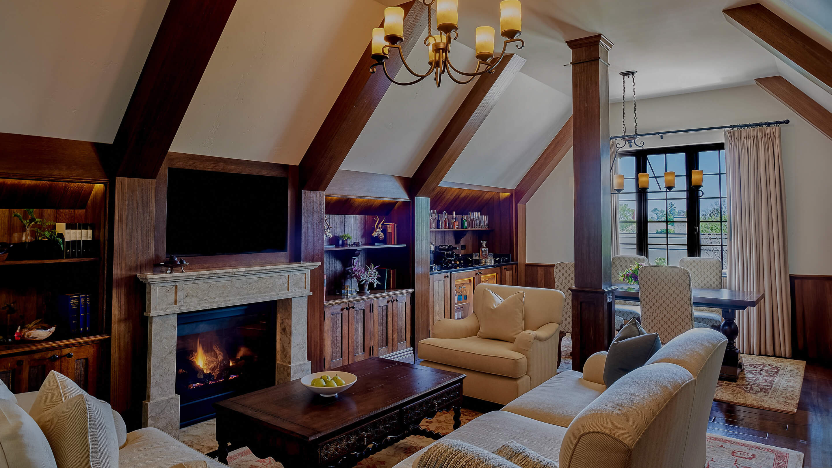 Exposed beams and crackling flames create intimate ambiance in this refined sitting room, where plush seating and rich woodwork invite lingering conversations over evening cocktails.
