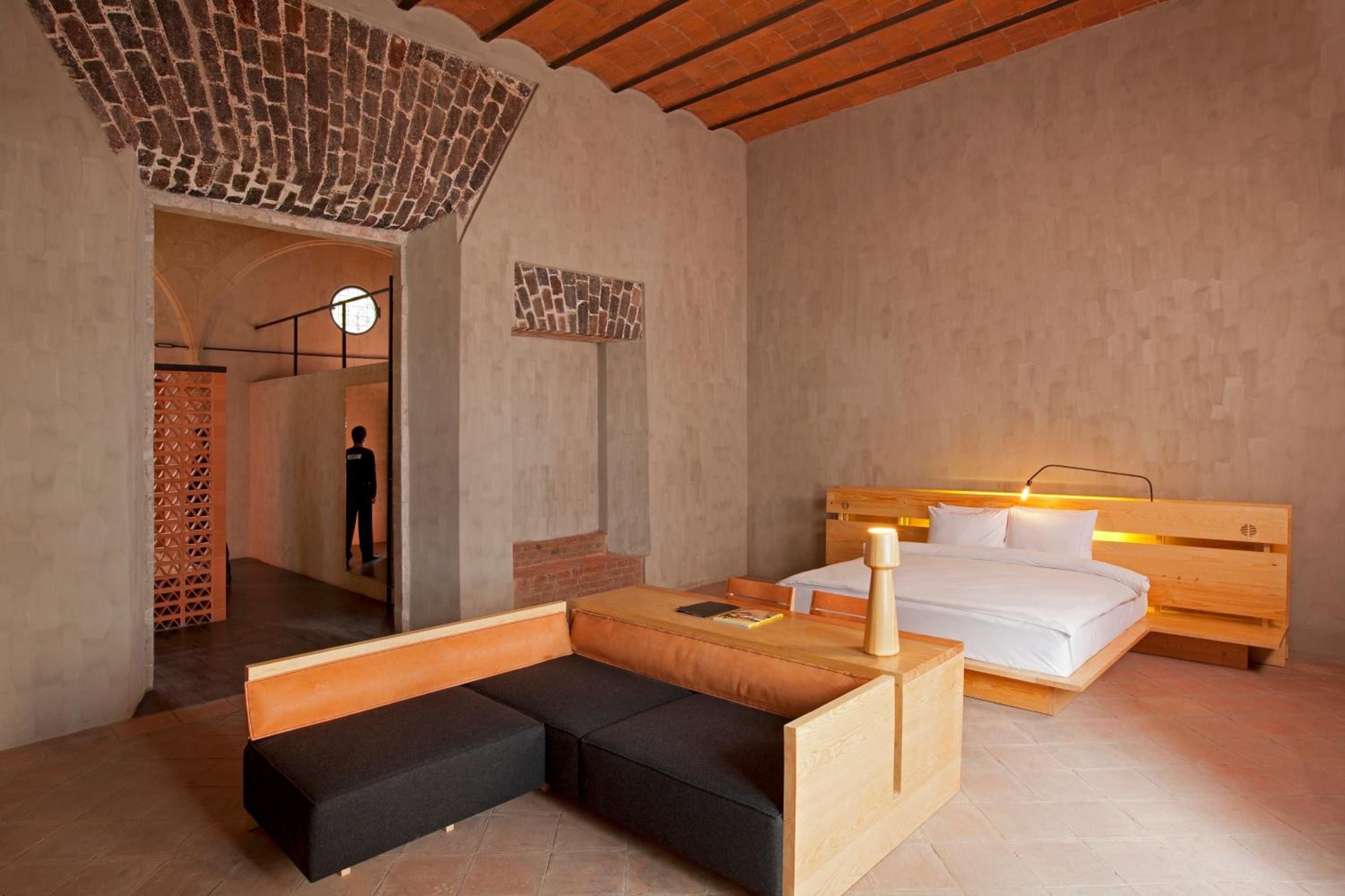 Warm wood furnishings and exposed brick vaulting create an intimate sanctuary where contemporary Mexican design meets colonial architecture in this thoughtfully appointed suite.
