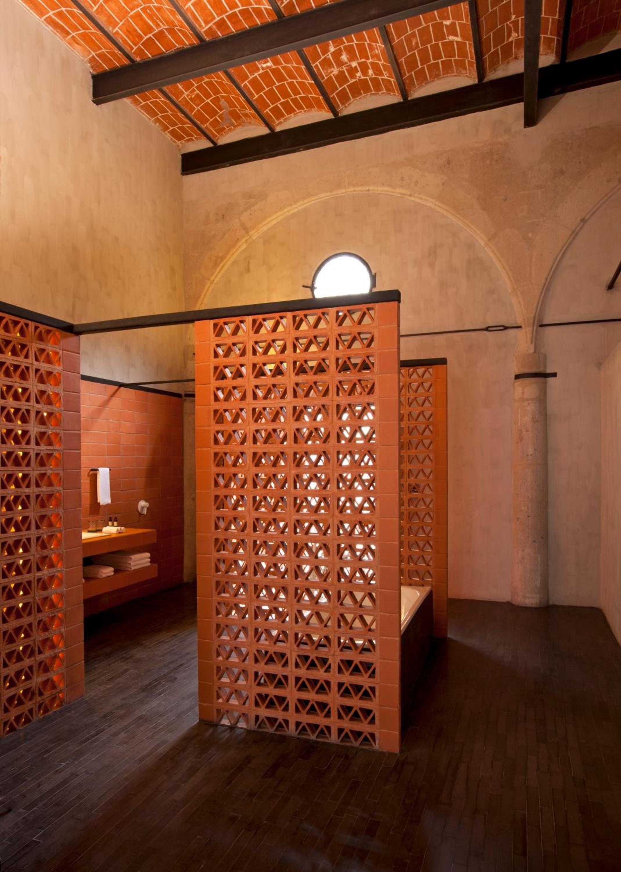 Perforated terracotta screens filter golden light through this serene wellness sanctuary, where vaulted brick ceilings and warm adobe walls create an intimate cocoon of calm.