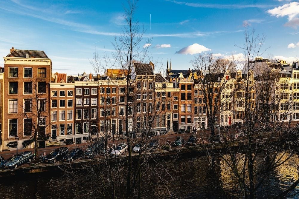 Golden afternoon light bathes Amsterdam's iconic canal houses, where centuries-old brick facades and bare winter trees frame the waterways outside this intimate boutique retreat.