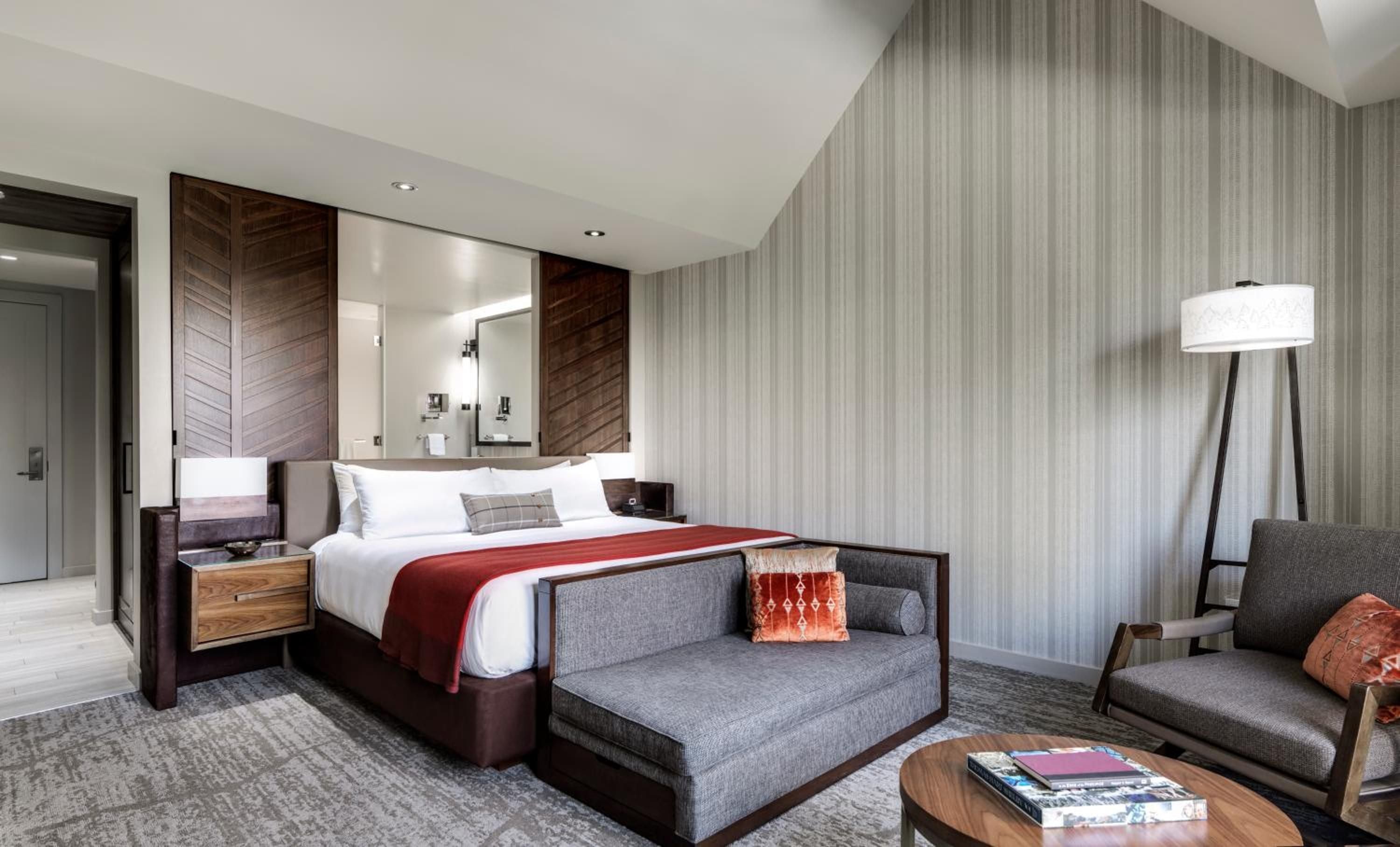 Warm wood paneling and textured wallpaper create an intimate sanctuary, while the plush daybed invites lingering over morning coffee with lake views beyond.