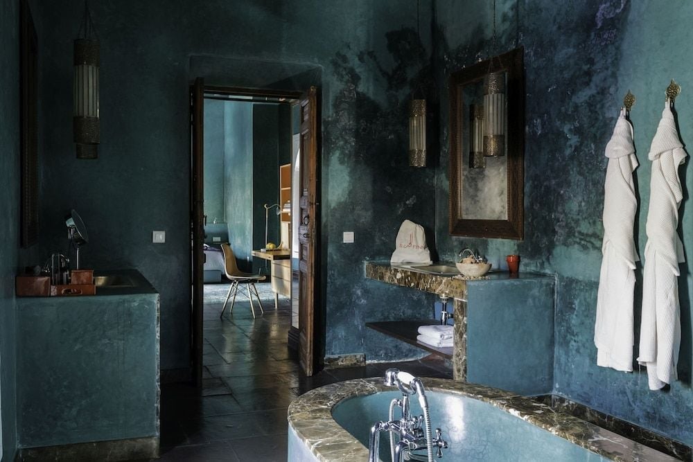 Tadelakt walls in deep indigo create an intimate cocoon around the marble-trimmed bathtub, where Moroccan craftsmanship meets contemporary luxury in perfect harmony.