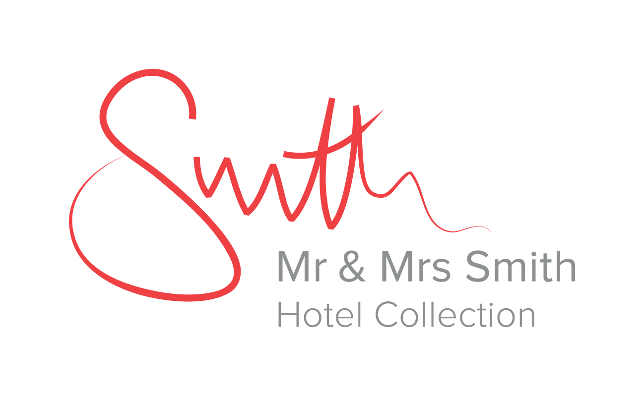Elegant script lettering in coral red flows across clean white space, embodying the sophisticated branding of this boutique hotel collection's refined aesthetic.