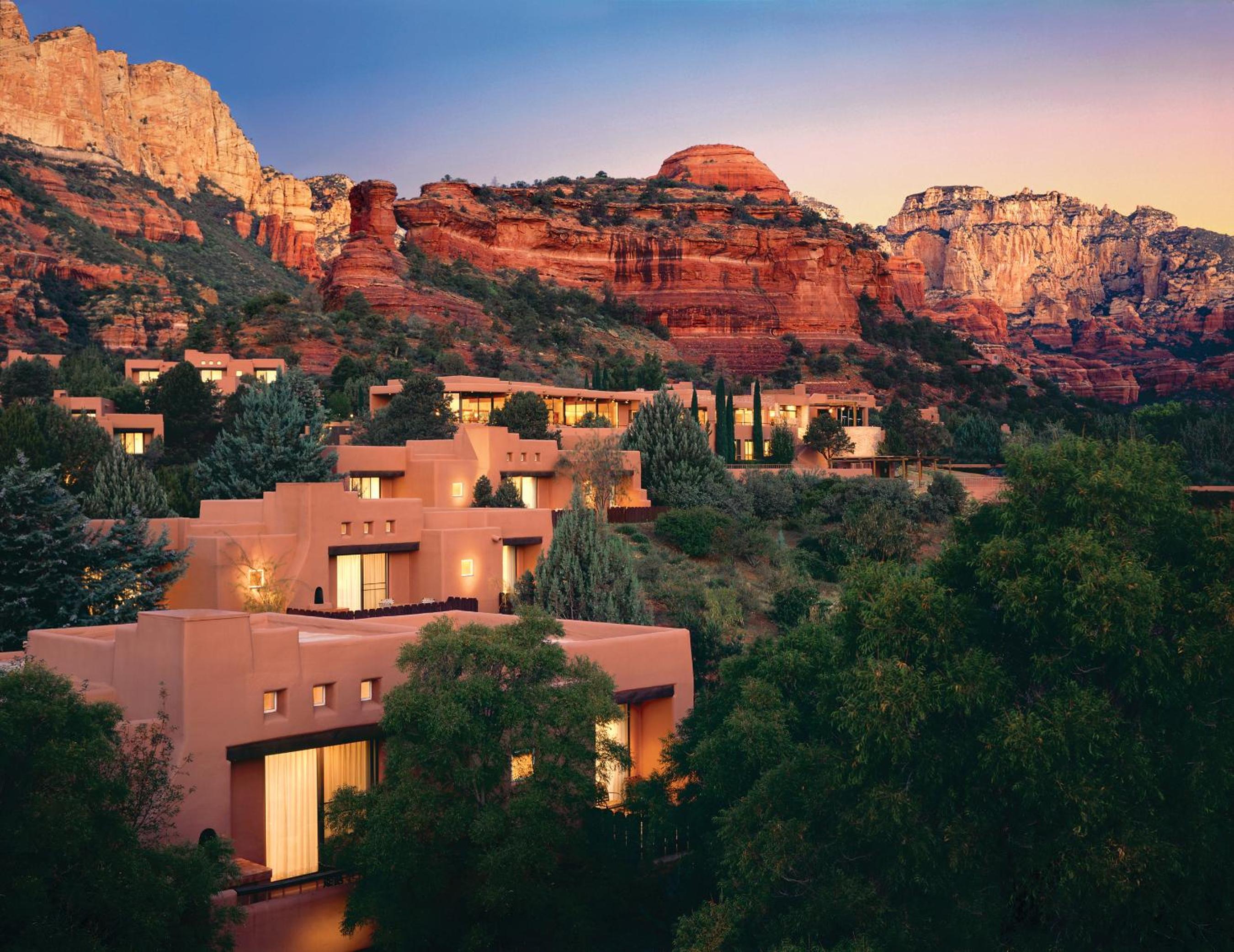 Adobe-style casitas glow warmly against Sedona's iconic red rocks as twilight paints the desert sky in graduating shades of rose and lavender.