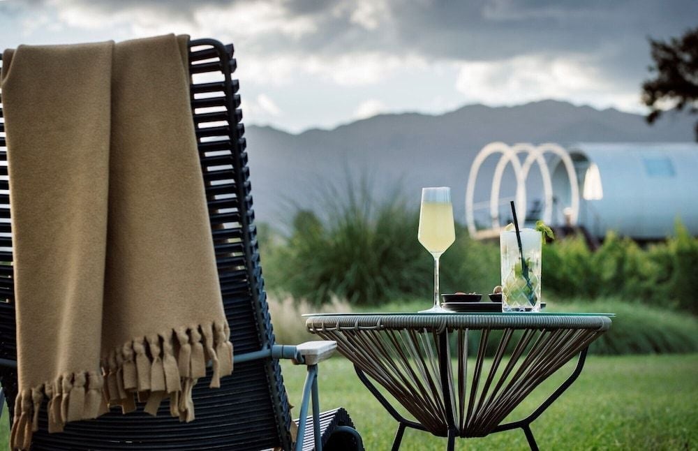 Golden hour light catches champagne glasses and woven textures on the terrace, where Mendoza's Andes create a dramatic backdrop for intimate moments.
