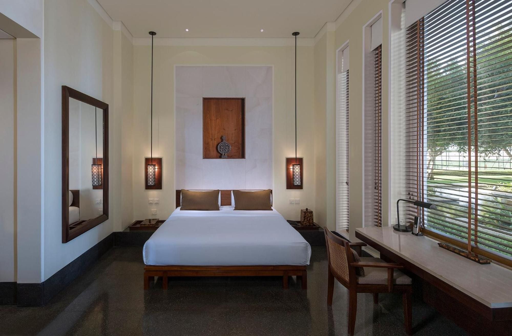 Crisp white linens contrast beautifully with warm wood furnishings and traditional pendant lights, while shuttered windows filter gentle natural light across polished floors.