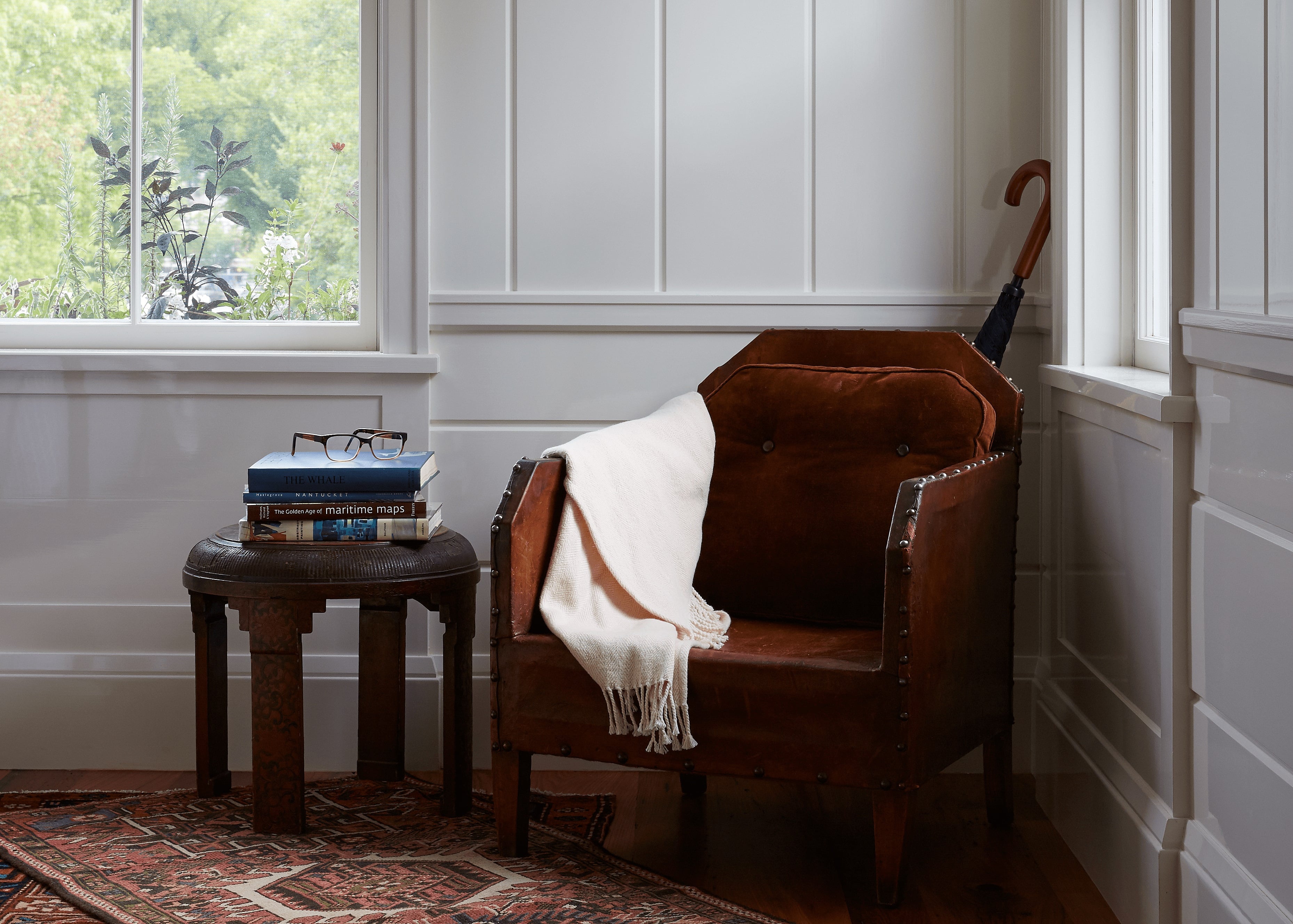 Cognac leather and worn Persian rugs create an intimate reading nook, where afternoon light filters through mullioned windows onto stacked maritime maps and a well-loved walking stick.