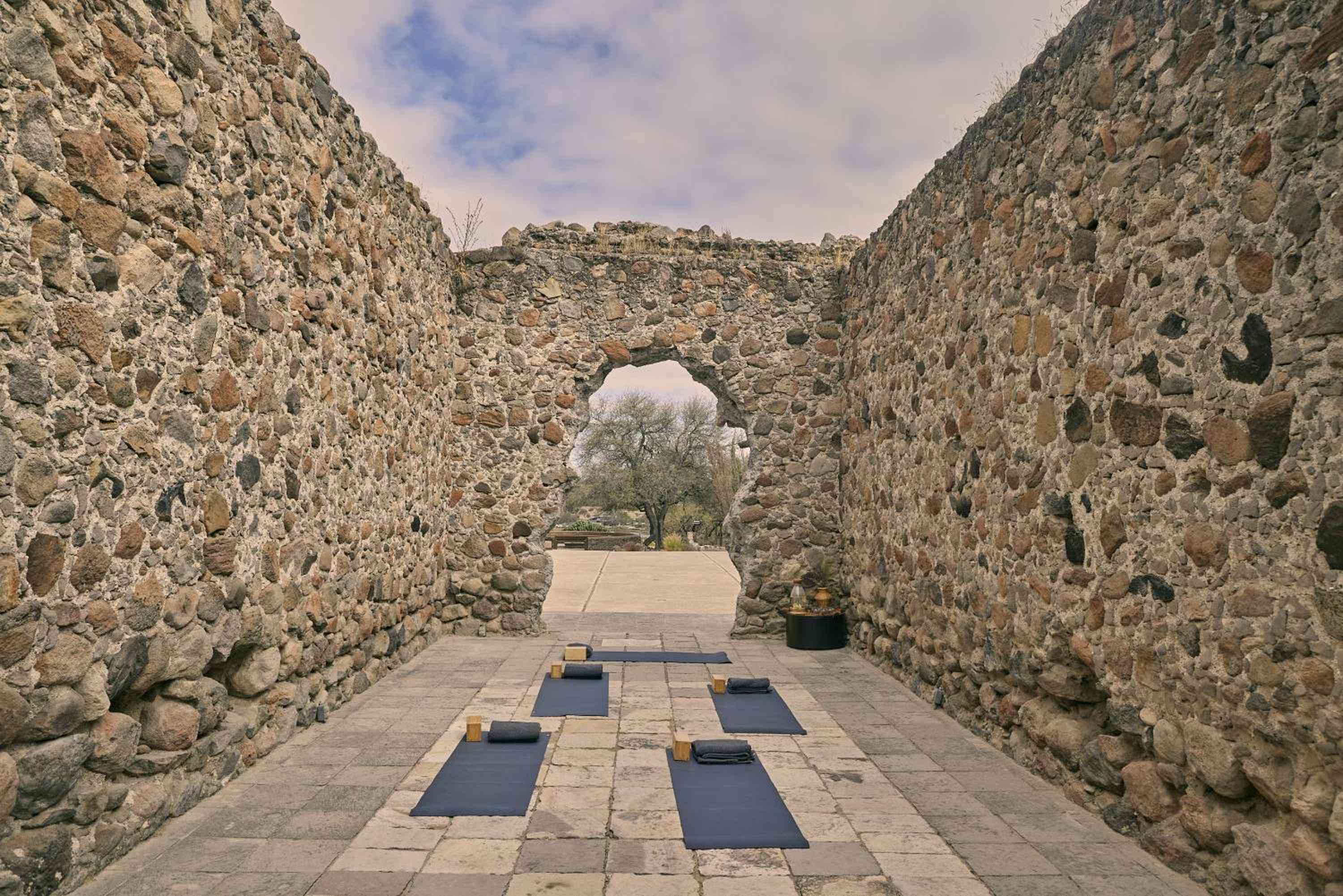 Ancient stone walls frame modern yoga mats in this contemplative wellness space, where volcanic rock architecture creates a cathedral-like sanctuary for morning meditation sessions.