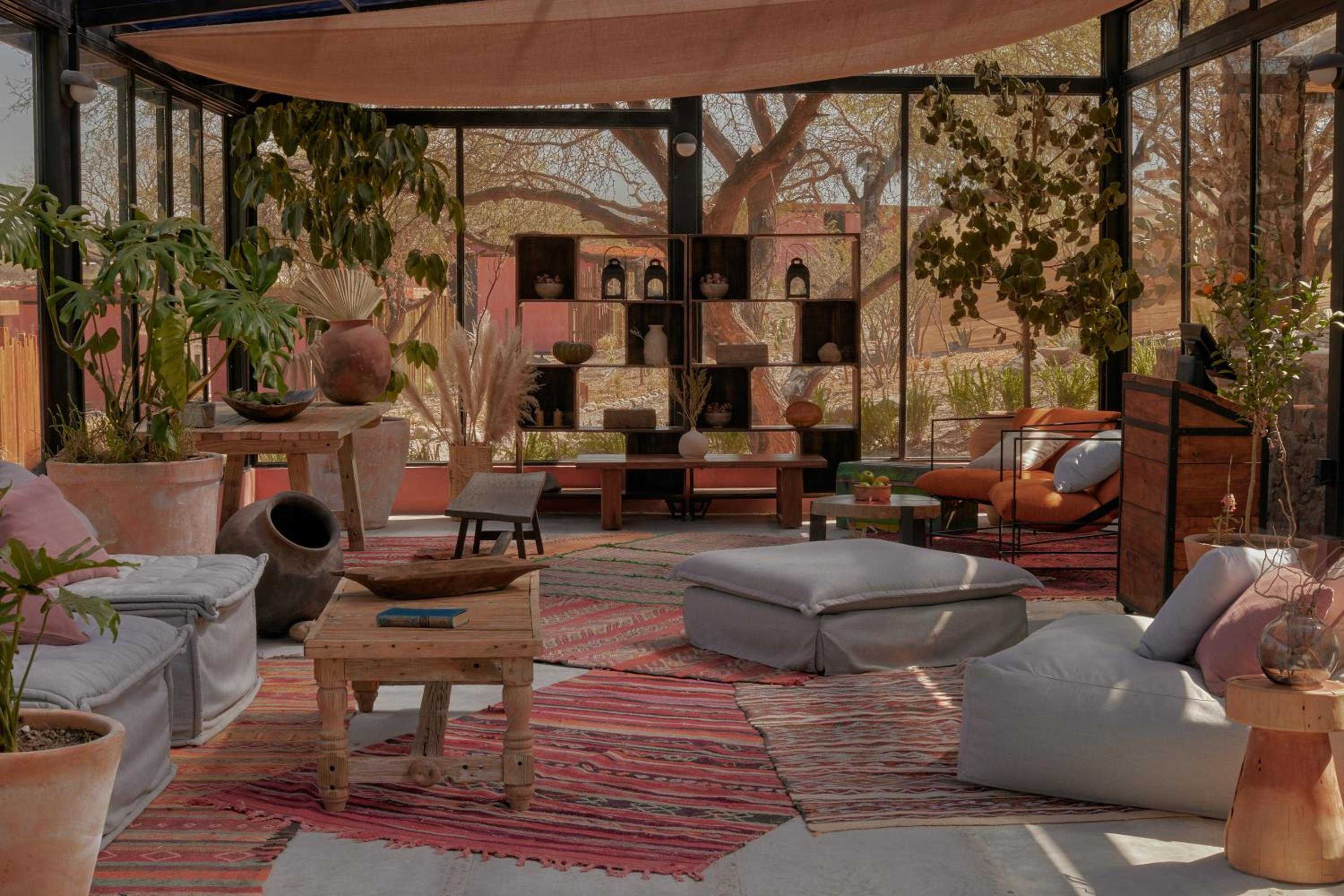 Moroccan-inspired shelving displays handcrafted pottery beneath a canvas canopy, while striped kilim rugs and oversized floor cushions create an inviting bohemian sanctuary.