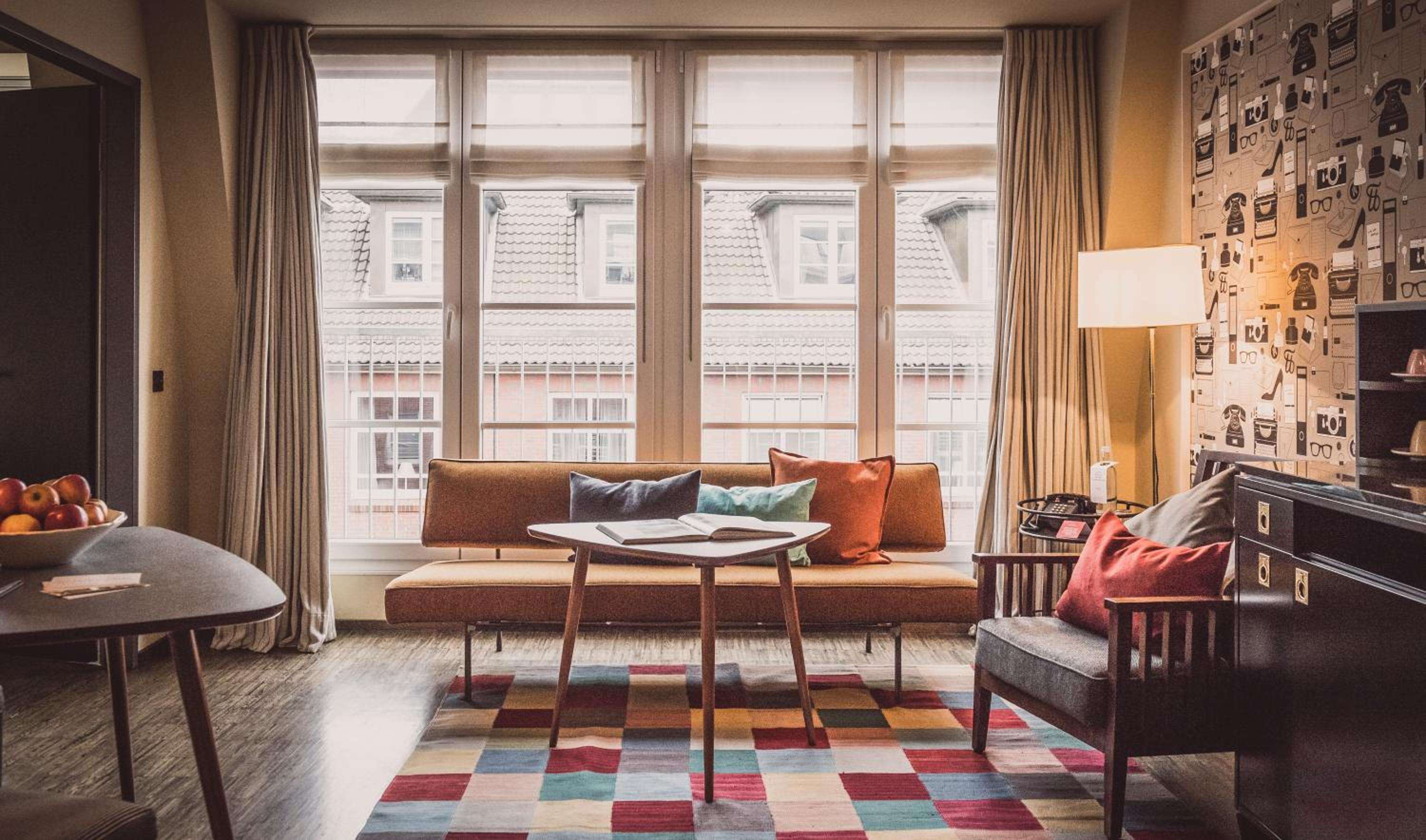 Mid-century furnishings and geometric textiles create an intimate living space where warm afternoon light filters through tall windows overlooking Bergen's charming rooftops.