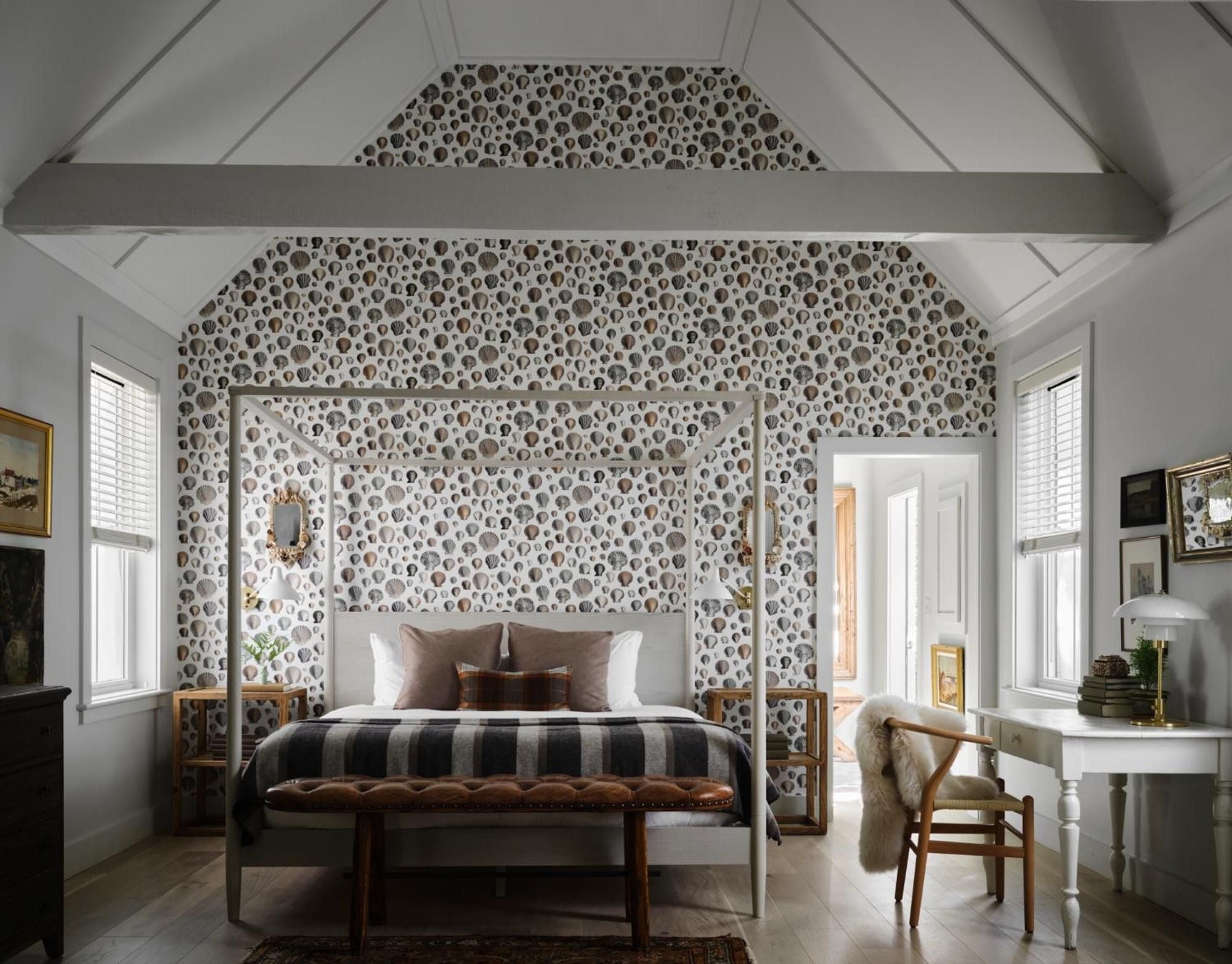 Exposed beams frame a canopy bed adorned with whimsical polka-dot wallpaper, while morning light filters through plantation shutters in this charming attic retreat.