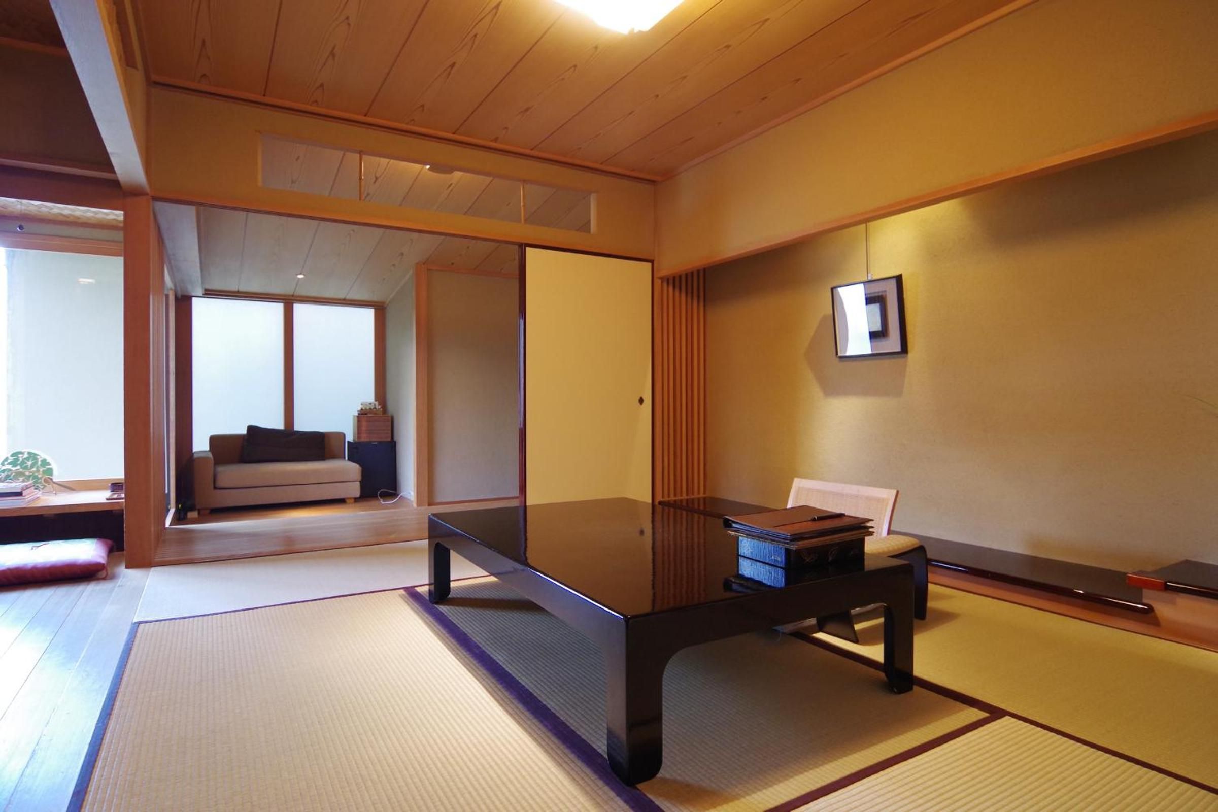 Warm wood beams and traditional tatami mats create an intimate sanctuary, where sliding screens partition spaces with gentle precision and natural light pools softly.