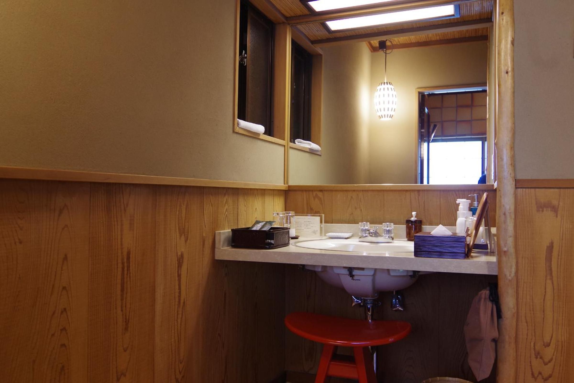 Warm wood paneling and traditional craft details create an intimate washroom sanctuary, where modern amenities blend seamlessly with ryokan heritage at this centuries-old Kyoto inn.