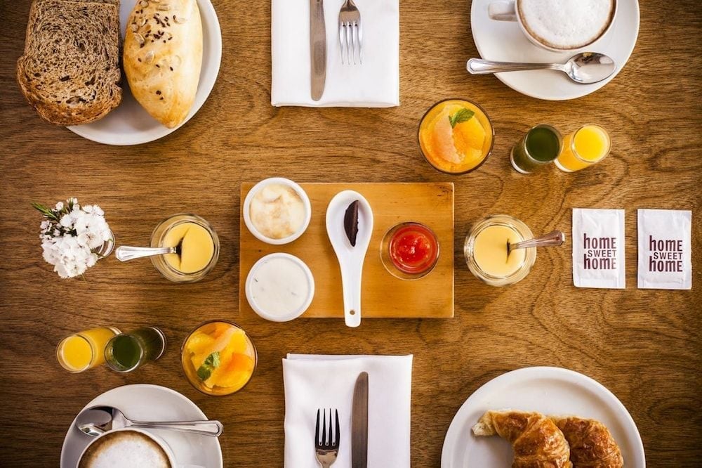Morning sunlight streams across polished wood as artisanal spreads, fresh pastries, and golden juices create an intimate breakfast tableau that embodies Buenos Aires' unhurried café culture.