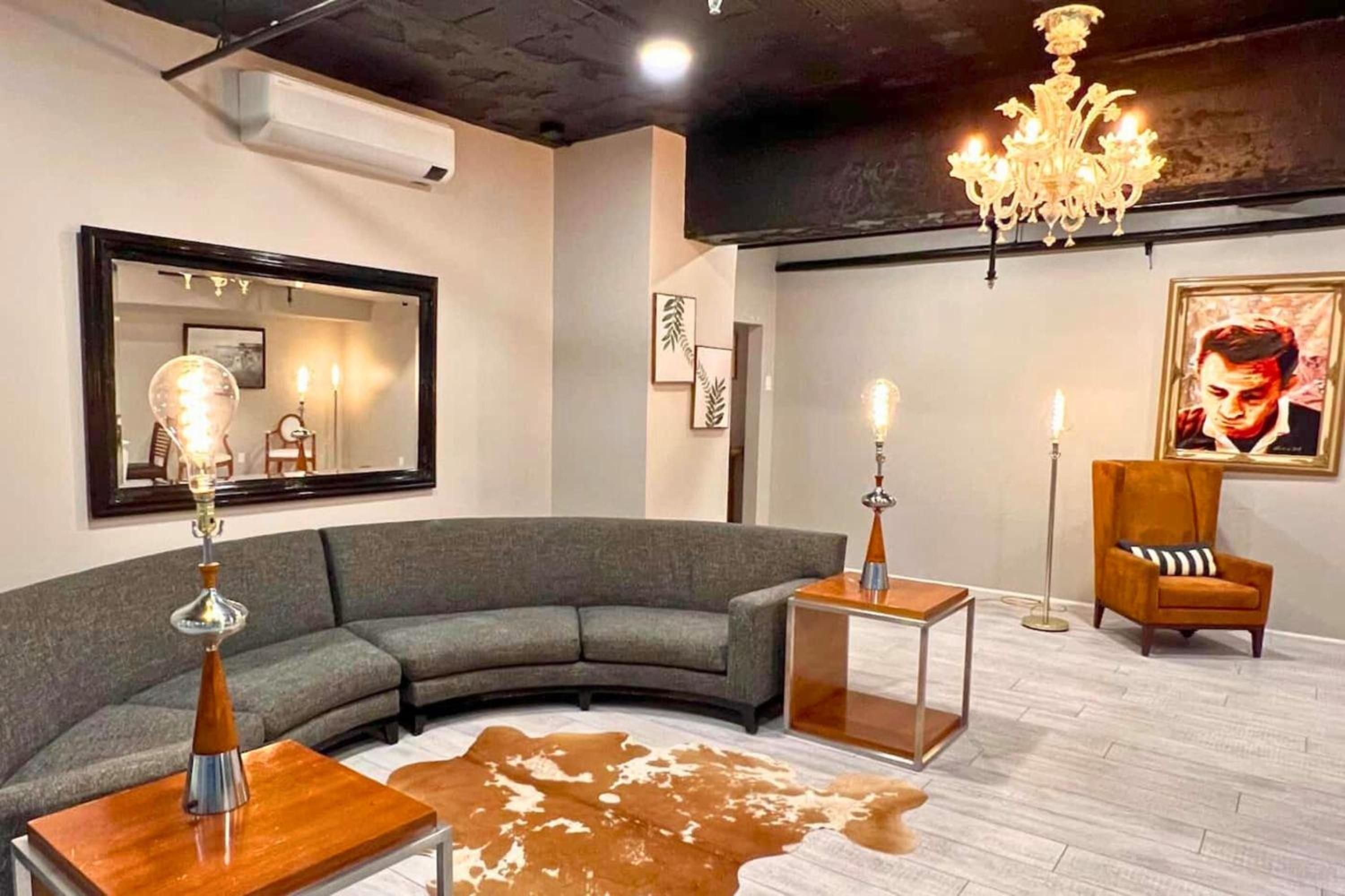 Curved charcoal seating and warm amber lighting create an intimate mid-century haven, where crystal chandeliers cast gentle shadows across polished concrete floors.