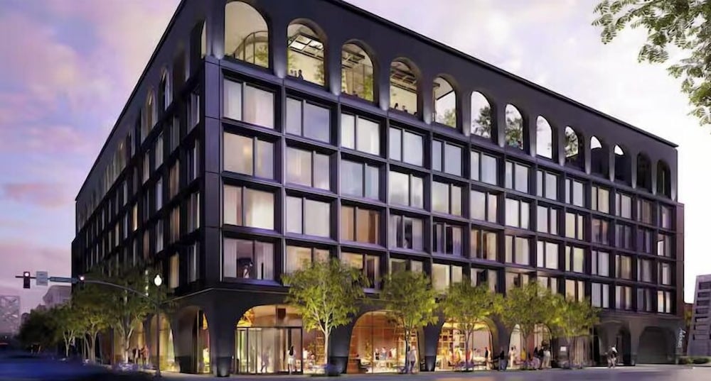 Arched windows crown this striking dark facade where contemporary geometry meets classical proportions, creating an elegant urban sanctuary beneath dusky purple skies.