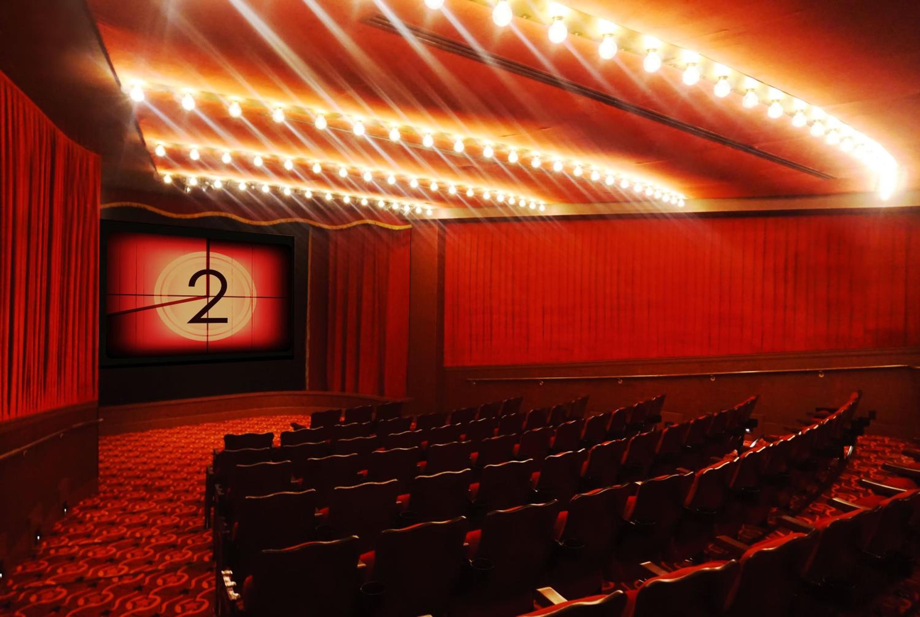 Plush crimson seating and dramatic curved ceiling lights create an intimate screening room where classic cinema countdown meets contemporary luxury design.