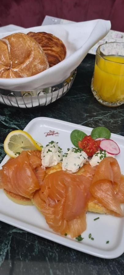 Silky smoked salmon drapes golden brioche while herb-flecked cream cheese adds freshness to this elegant breakfast spread, accompanied by flaky pastries and bright orange juice.