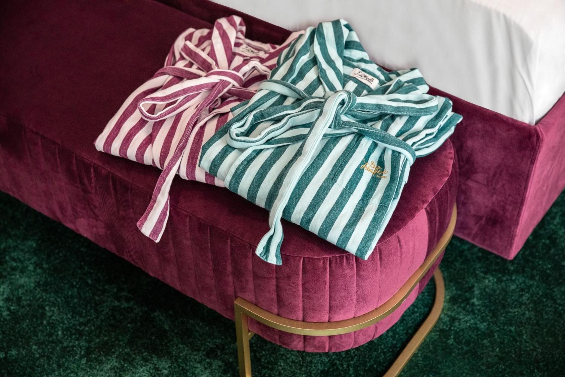 Striped robes in burgundy and teal rest on plush velvet seating, where thoughtful touches reveal the hotel's attention to guest comfort and style.
