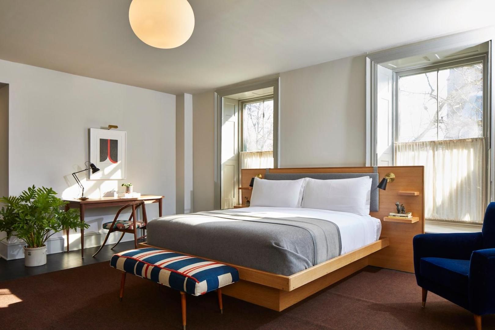 Mid-century walnut furnishings and striped textiles create a sophisticated retreat, where morning light filters through tall windows onto polished concrete floors.