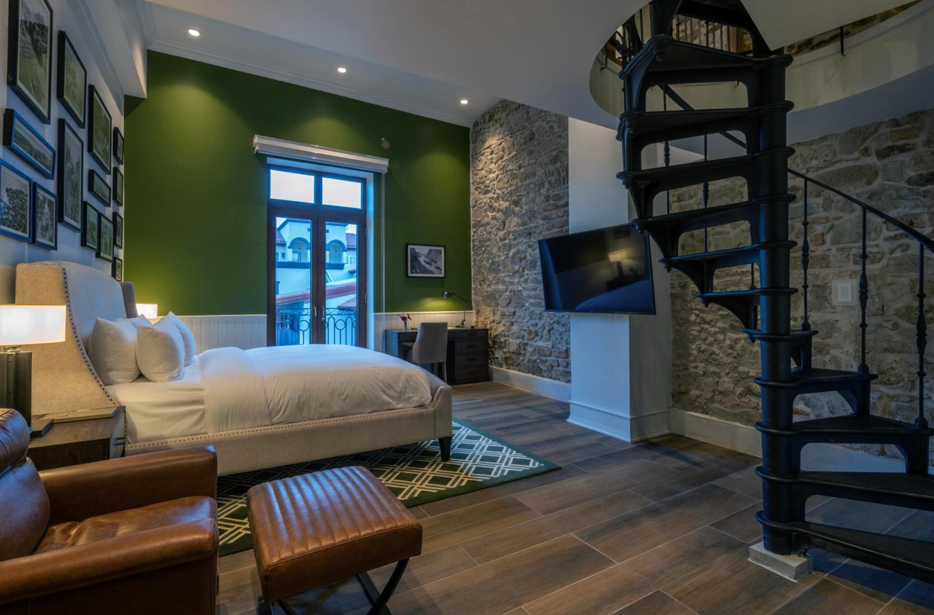 Stone walls meet contemporary luxury in this duplex suite, where emerald accent walls and spiral stairs create an intimate loft-like sanctuary above Cusco's cobblestone streets.