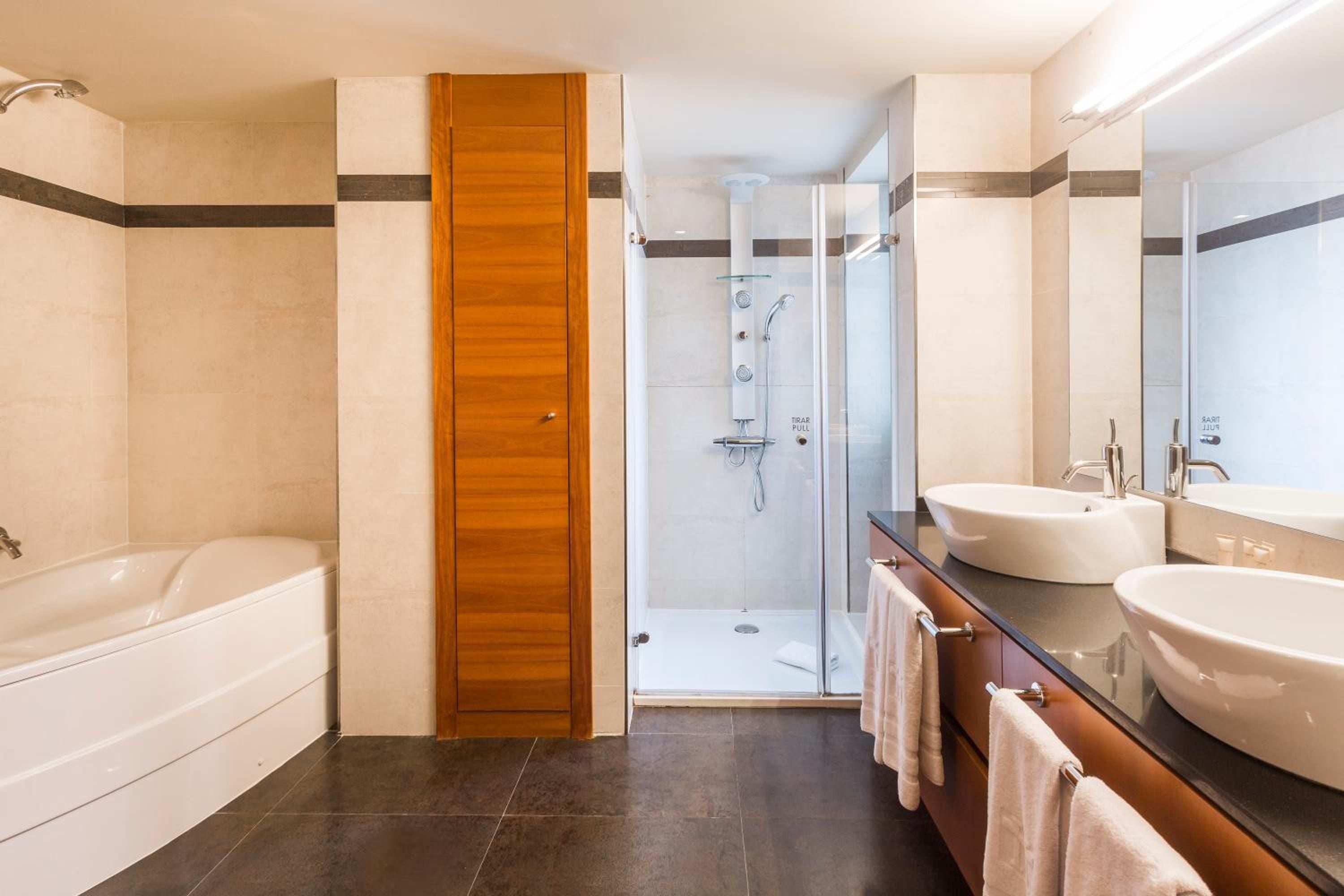 Warm wood accents and sleek vessel sinks create an inviting spa-like sanctuary, where soaking tubs and rainfall showers promise indulgent moments of retreat.