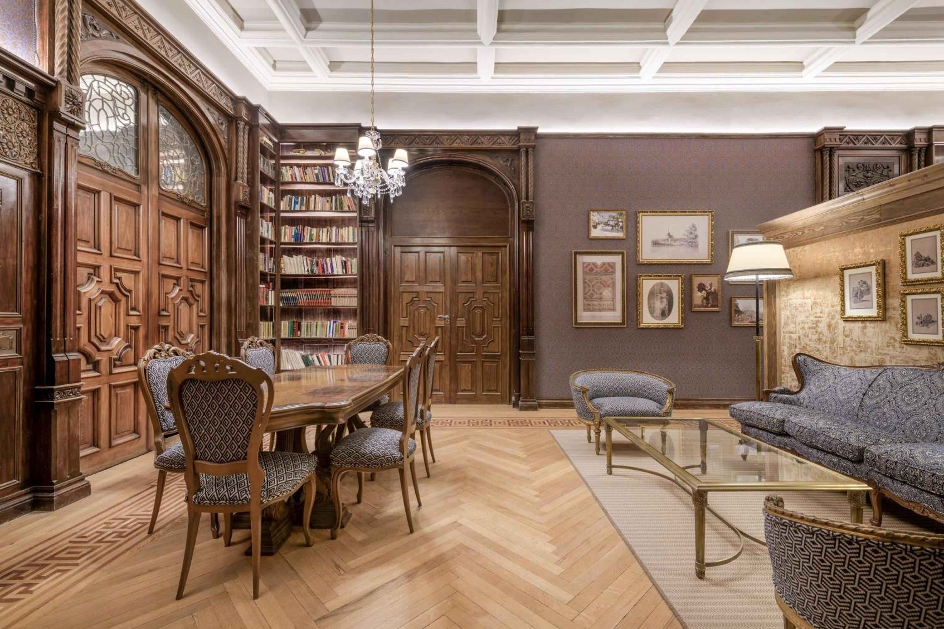 Rich walnut paneling and coffered ceilings frame this magnificent library lounge, where crystal chandeliers cast warm light over herringbone floors and plush velvet seating.