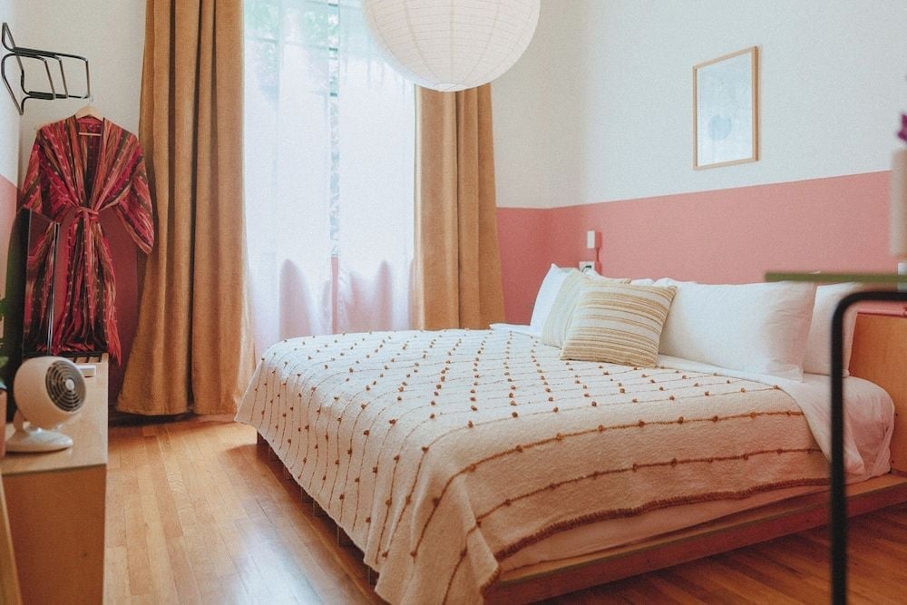 Warm terracotta walls frame a minimalist sanctuary where dotted linens and golden curtains create an intimate cocoon of Scandinavian-inspired serenity.