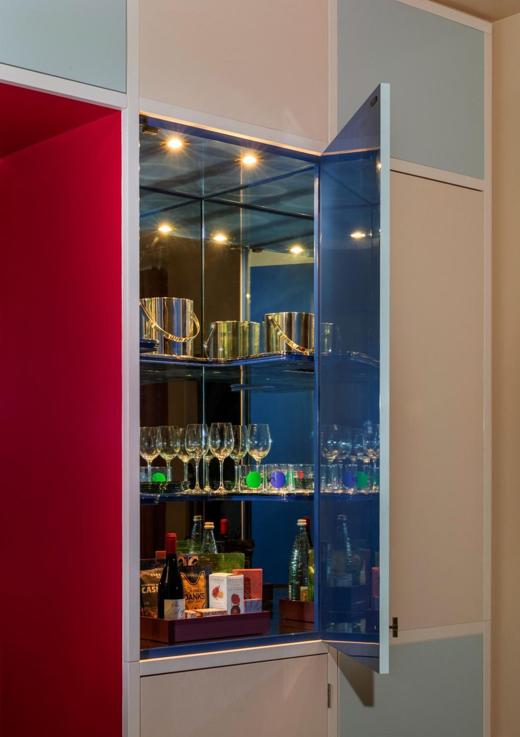Illuminated glass shelves showcase golden barware and crystal stemware in this sophisticated cabinet, where mirrored surfaces amplify the warm glow of integrated lighting.
