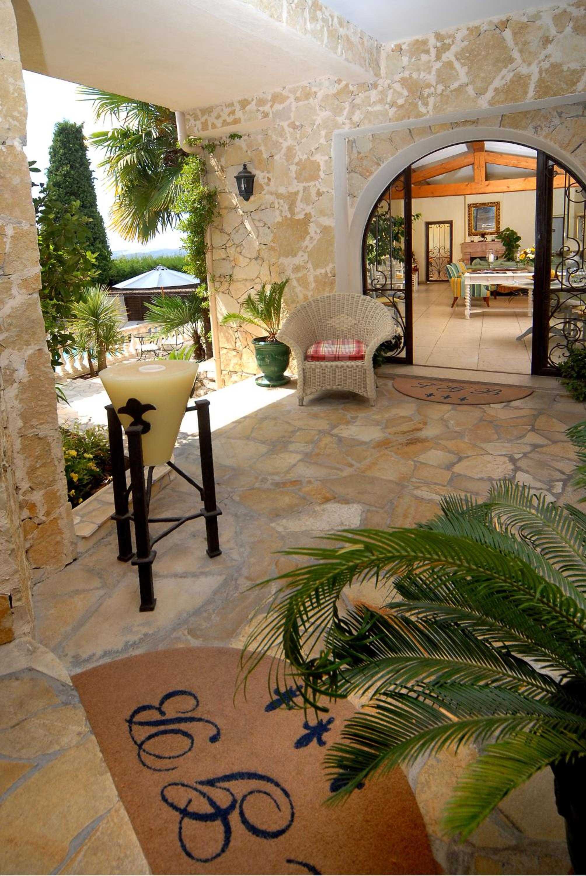 Stone archways frame sun-drenched terraces where wicker chairs invite lingering over morning coffee, while decorative floor mosaics hint at Mediterranean charm.