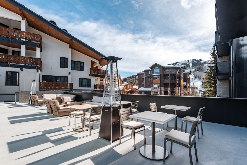 Alpine breezes drift across the rooftop terrace where pyramid heaters promise evening warmth amid Deer Valley's snow-dusted peaks and timber lodges.