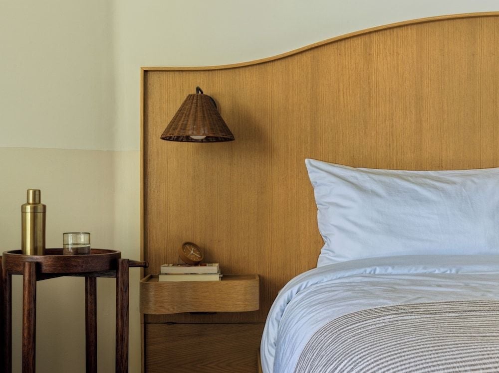 Warm wood headboards and woven pendant lights create intimate bedside moments, where brass cocktail shakers hint at evening rituals in thoughtfully curated guest rooms.