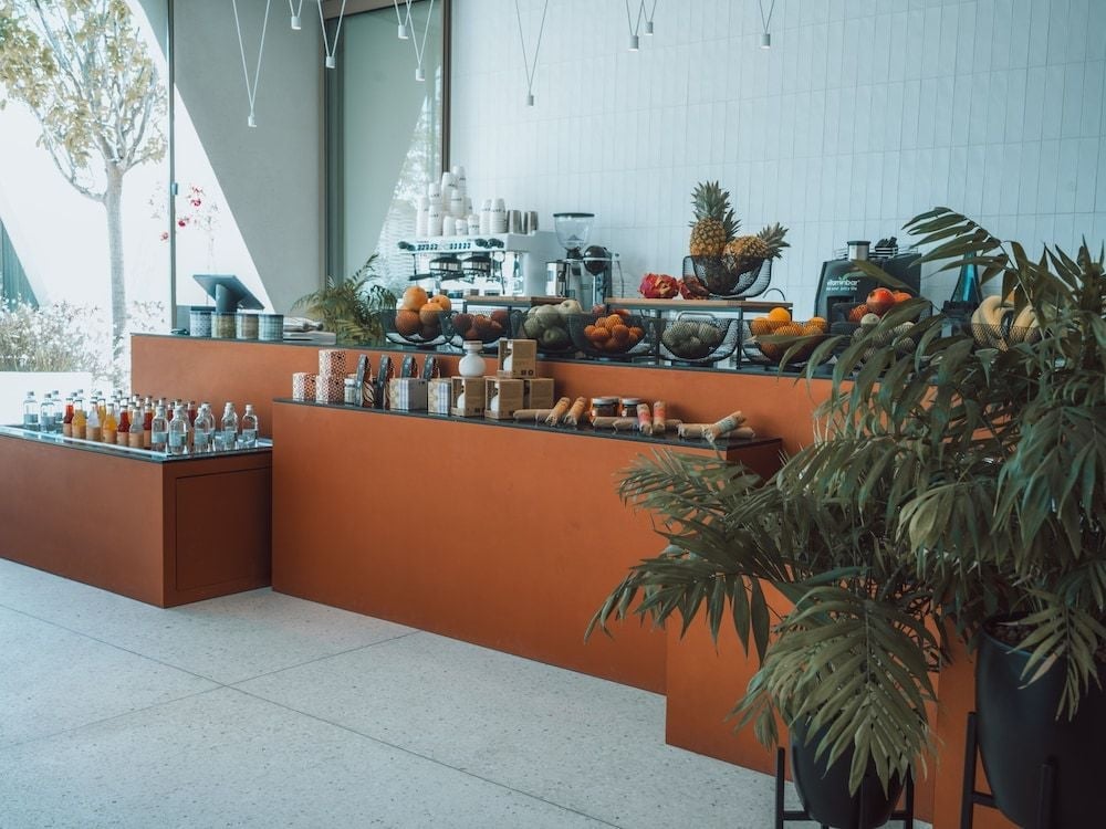 Fresh pineapples and vibrant citrus cascade across copper-toned surfaces, while tropical palms frame an inviting juice bar bathed in Mediterranean light.