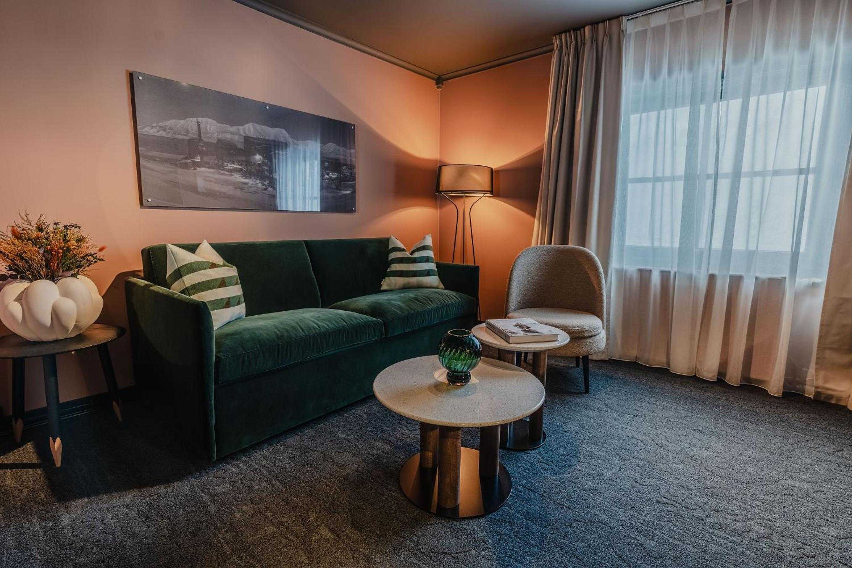 Emerald velvet seating and warm copper tones create an intimate retreat, where striped pillows and curated artwork reflect Funken Lodge's sophisticated mountain sensibility.