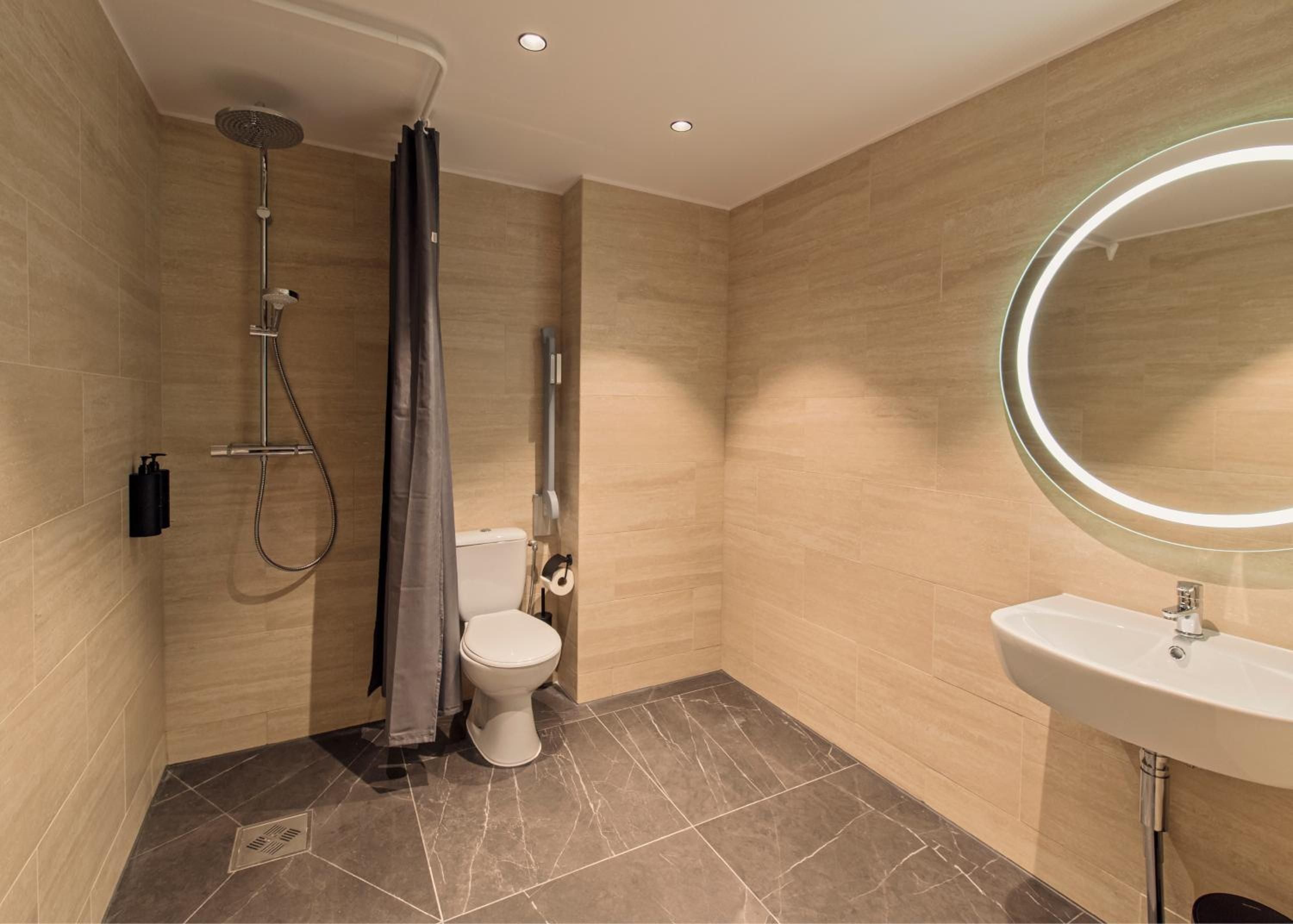 Warm travertine tiles and sleek fixtures create a spa-like sanctuary, where rainfall showers and illuminated mirrors elevate the everyday into pure indulgence.
