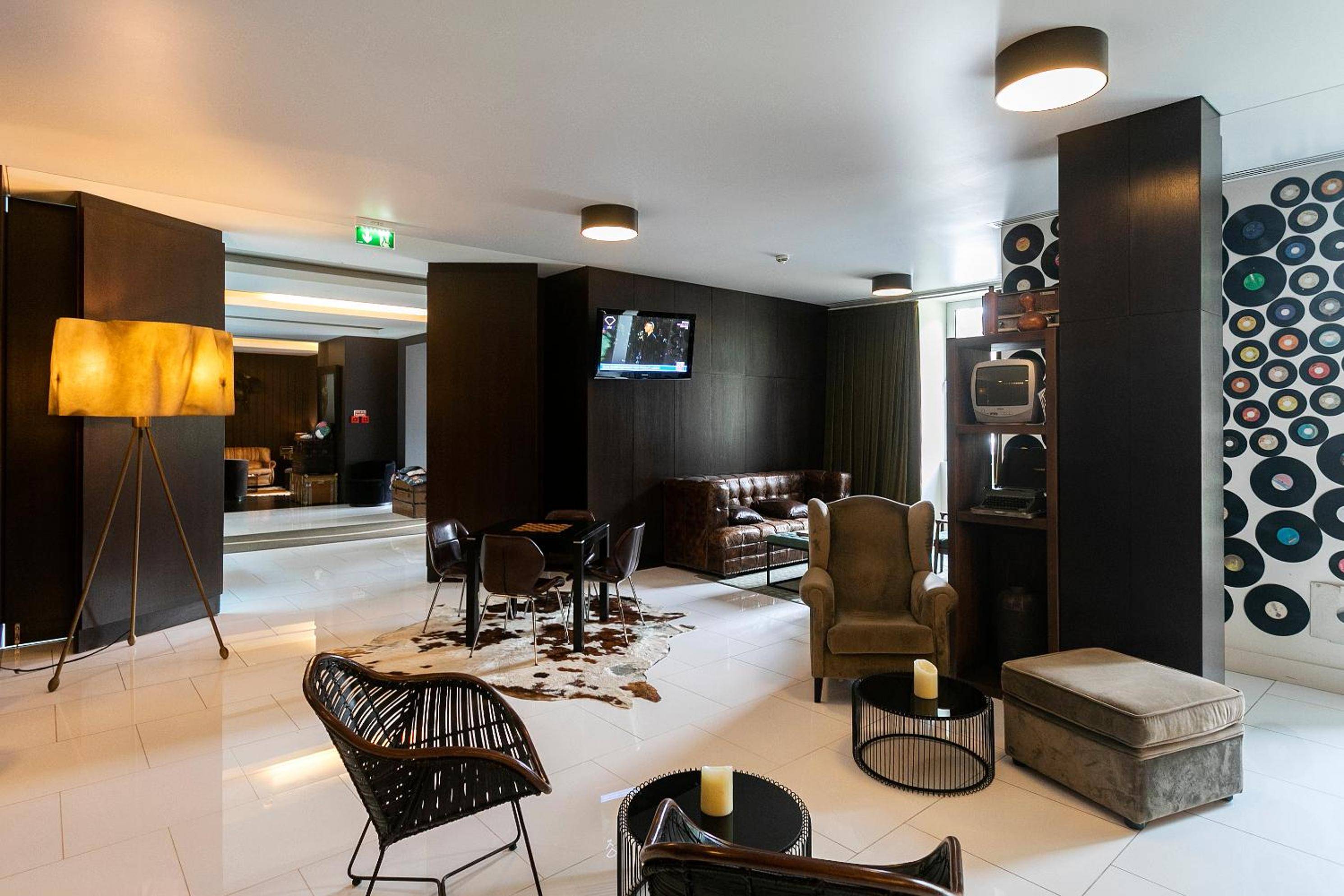 Vinyl records cascade down walls while leather seating and warm wood tones create an intimate lounge where mid-century design meets contemporary Portuguese hospitality.
