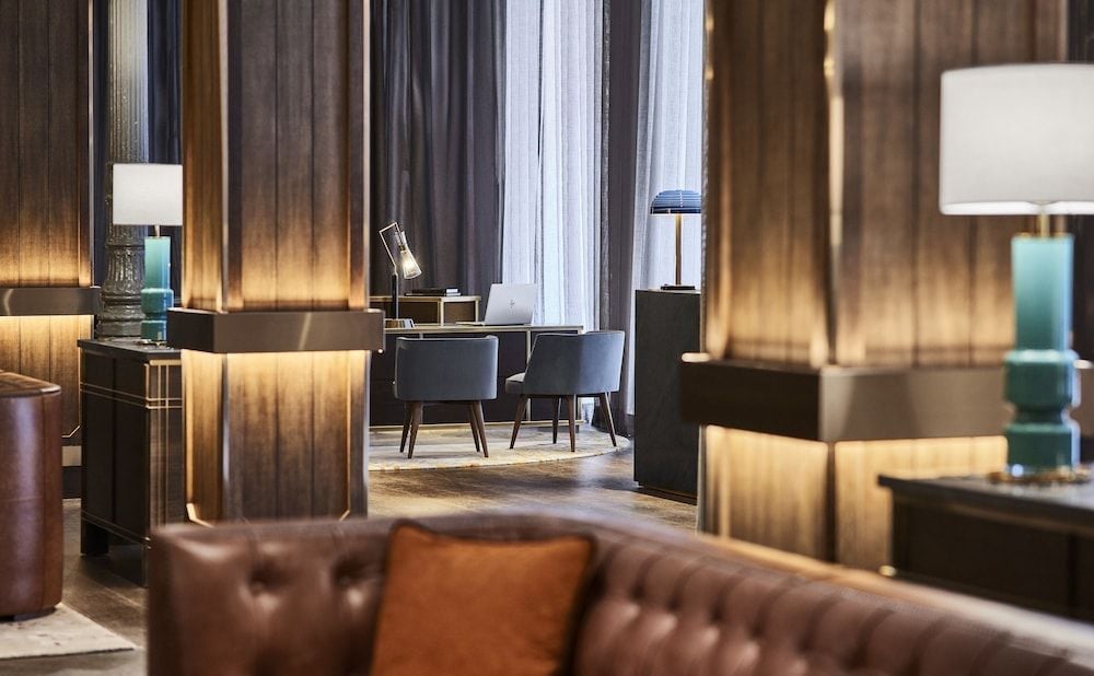 Warm wood paneling and jewel-toned accents create intimate conversation nooks throughout the sophisticated lobby, where soft lamplight pools on polished surfaces.