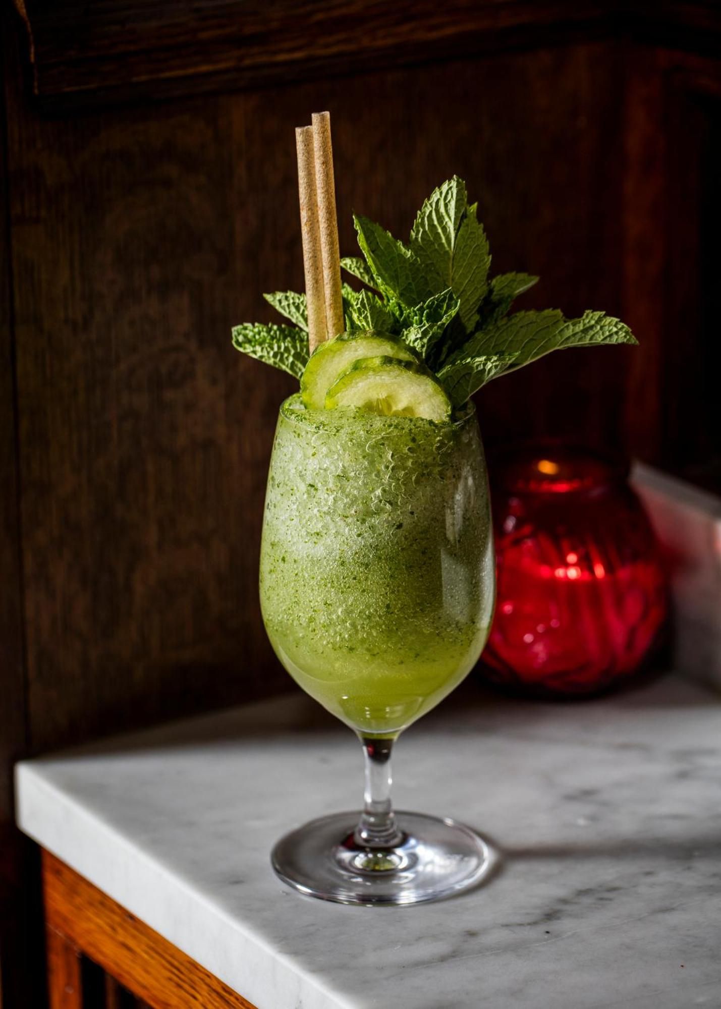 Crushed ice mingles with fresh mint and cucumber in a jade-hued cocktail, complete with bamboo straws—craft mixology meets botanical elegance in the hotel's intimate bar.
