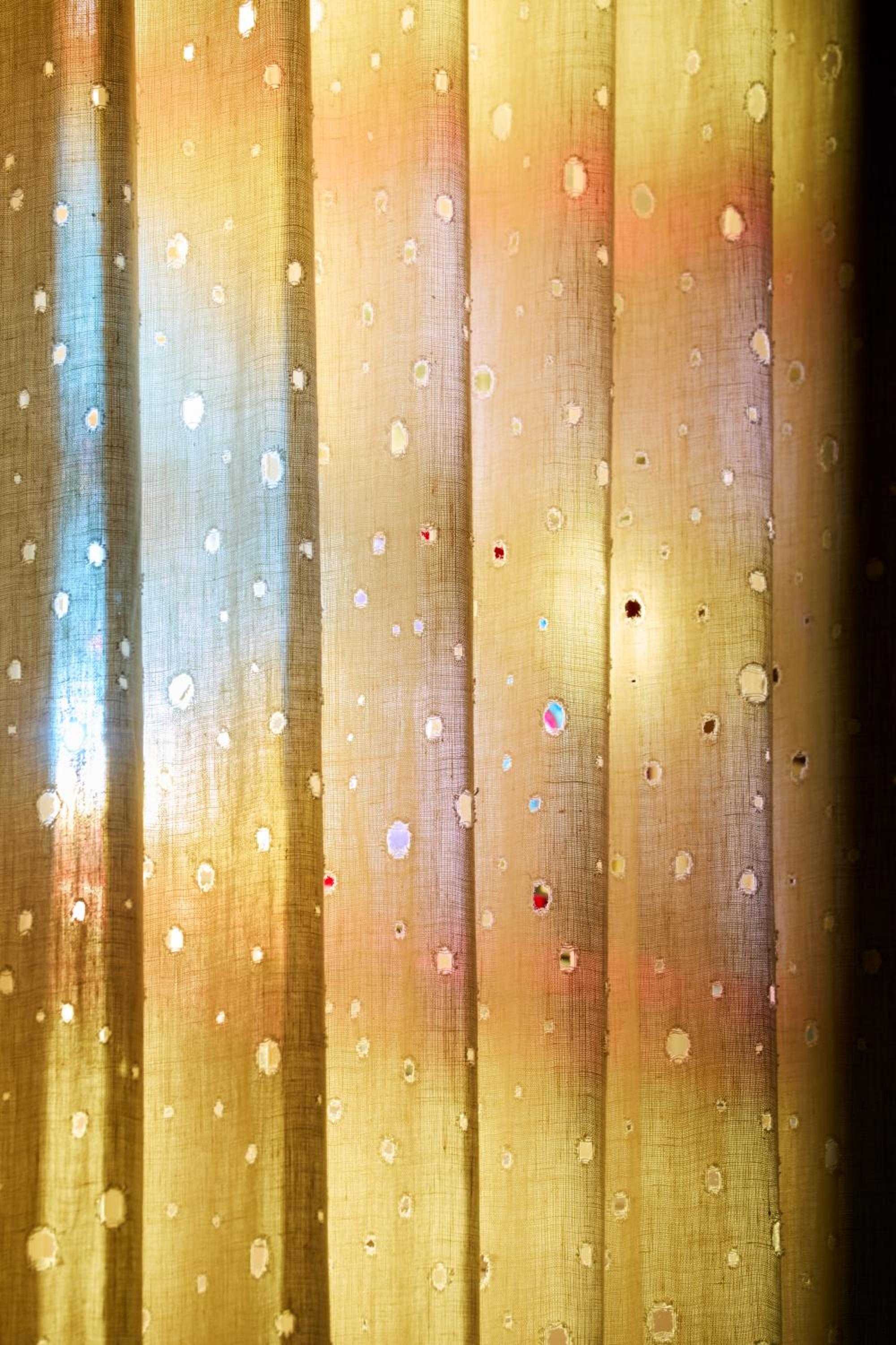 Golden afternoon light filters through time-worn curtains dotted with mysterious stains and stories, each mark a testament to the Chelsea's legendary bohemian past.